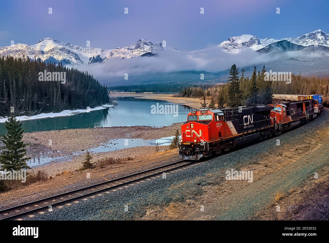 A Canadian National freight train traveling along a track through the rocky mountains of Alberta Canada. Stock Photo