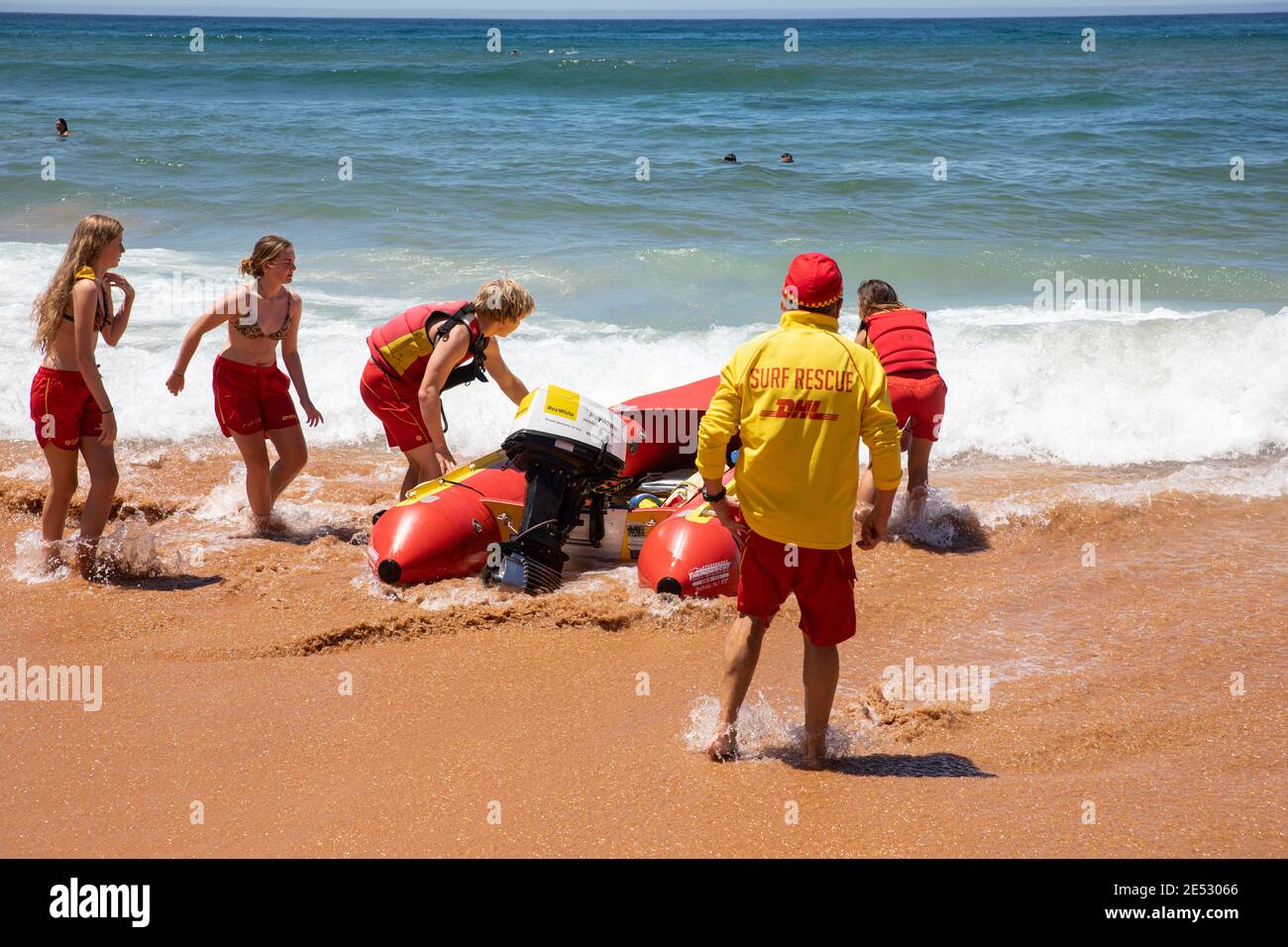 Volunteer surf rescue lifesavers launch inflatable red zodiac surf rescue boat at Bilgola Beach in Sydney,NSW,Australia Stock Photo