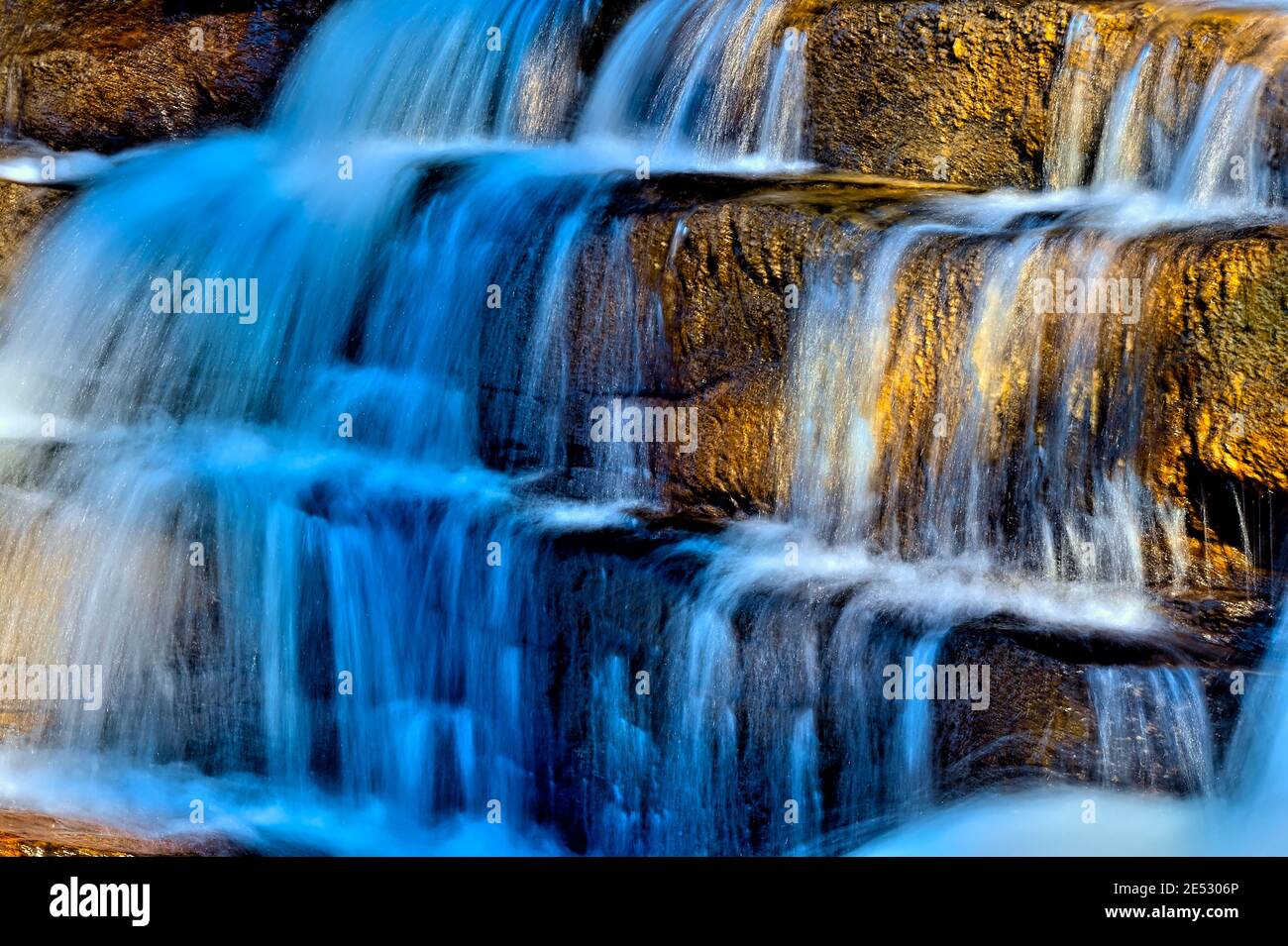 A beautiful lighted waterfall flowing over rock steps on the Athabasca river in Jasper National Park in Alberta Canada. Stock Photo