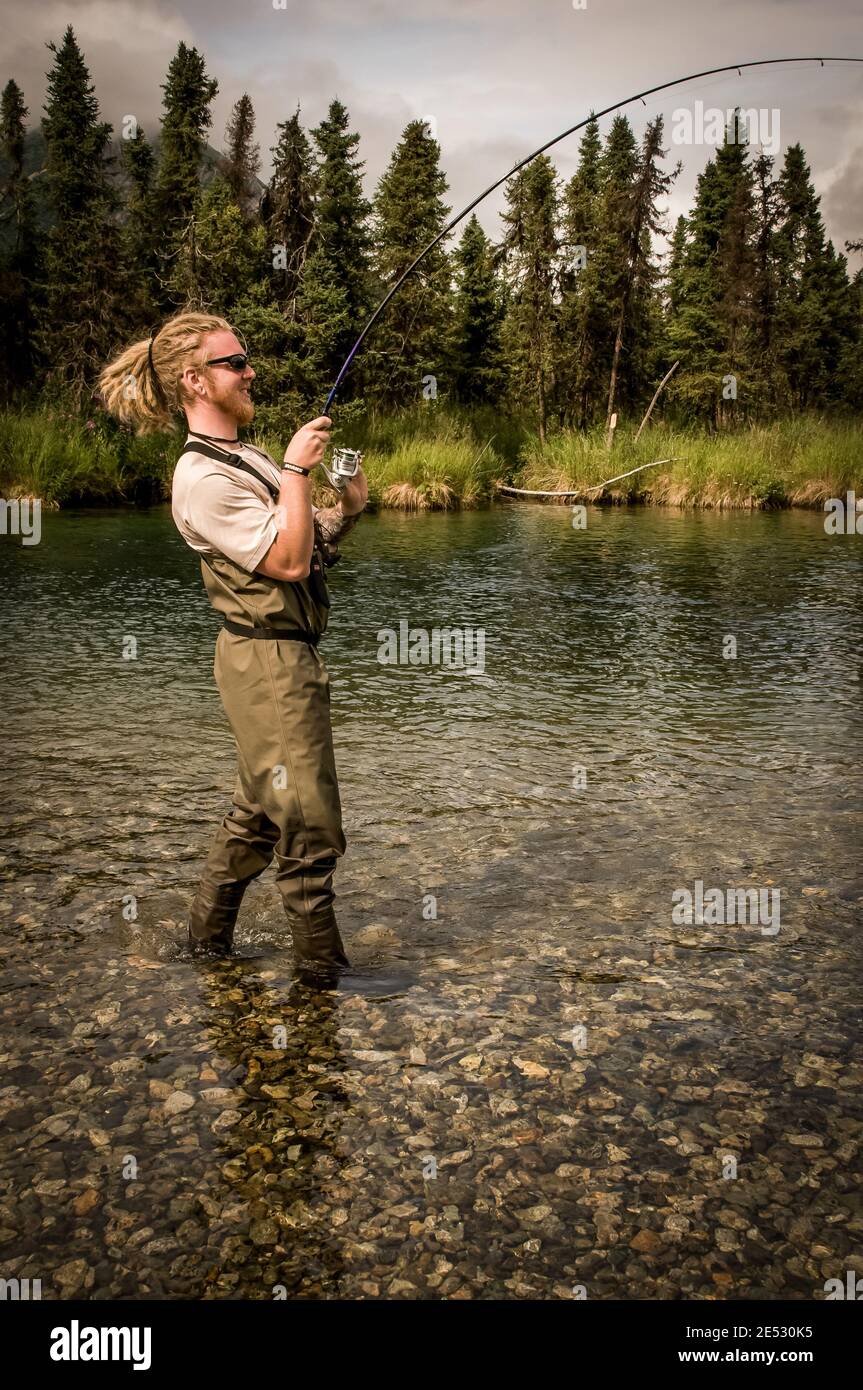 Man Reeling in a Salmon Catch near Lake Clark National Park Alaska Stock Photo