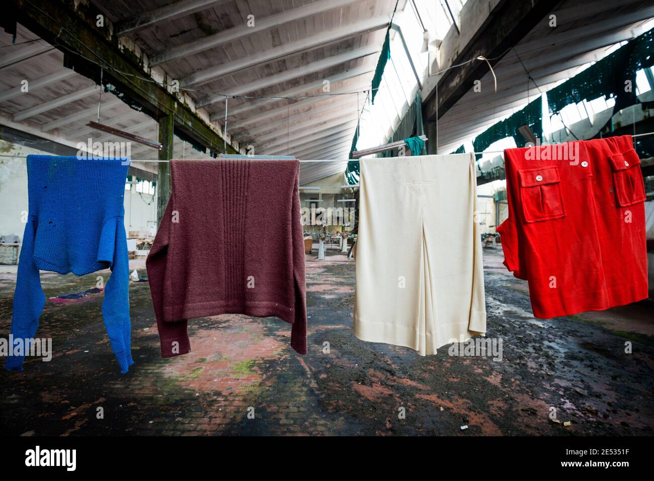 Close up of a line of colorful clothes left to dry in an old and abandoned Italian textile factory Stock Photo
