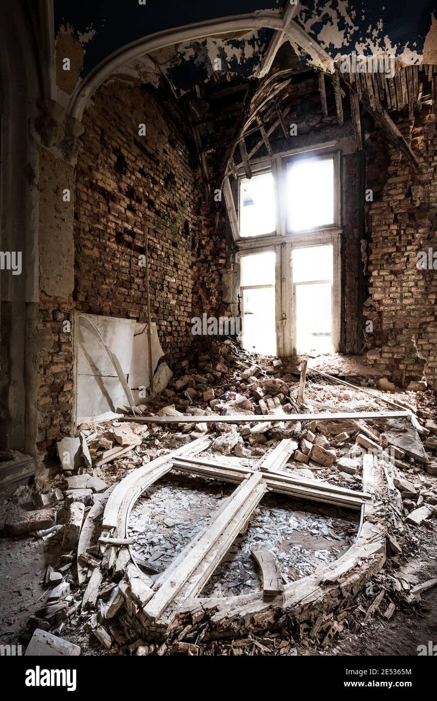 Interior of an ancient abandoned baroque castle, with a pointed arch window frame lying on the floor among debris Stock Photo