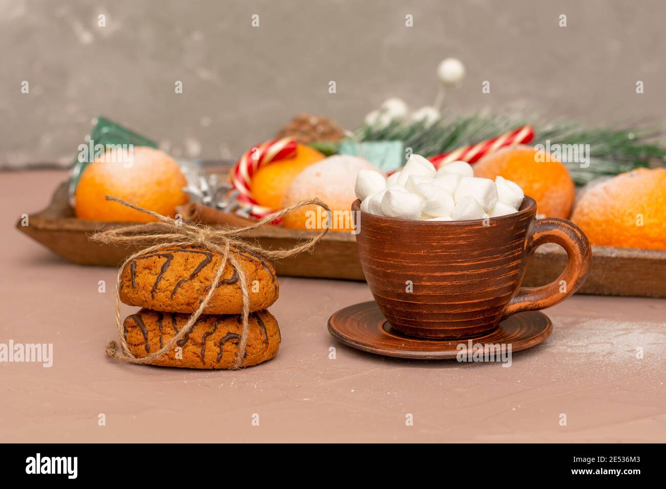 Romantic breakfast in winter. Coffee with marshmallows in clay cup and rope tied oatmeal cookies. Close-up, selective focus. Stock Photo