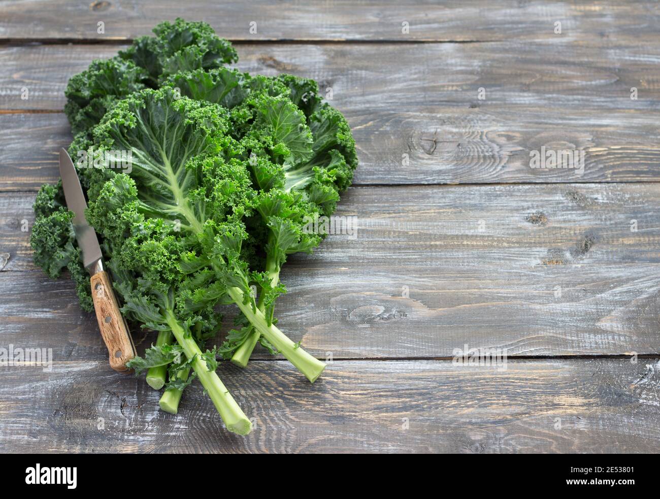 Fresh green curly kale leaves on a wooden table. selective focus. free space. rustic style. healthy vegetarian food Stock Photo