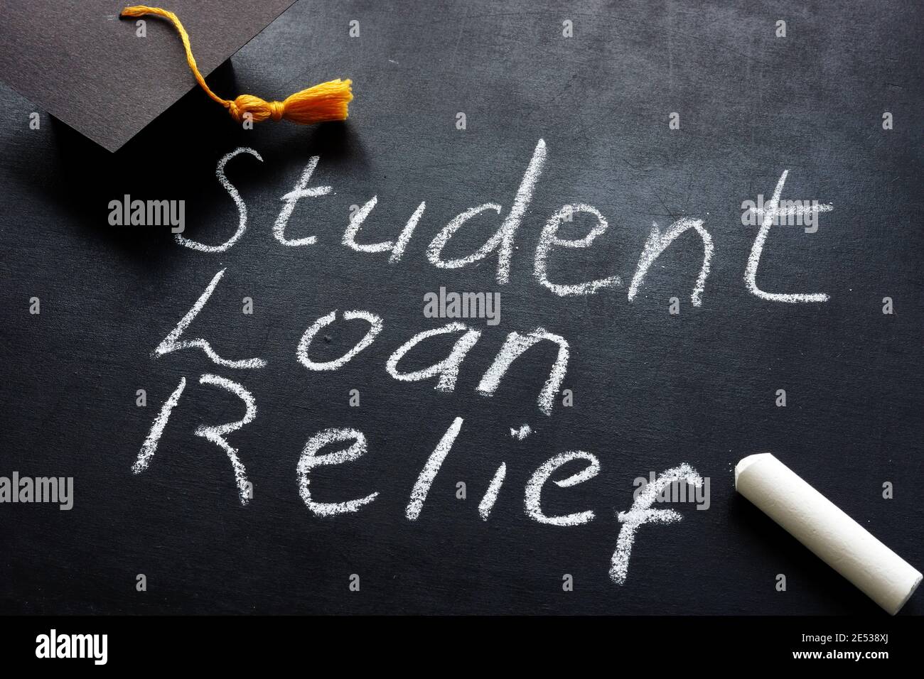 Student loan relief written on the blackboard and graduation cap. Stock Photo