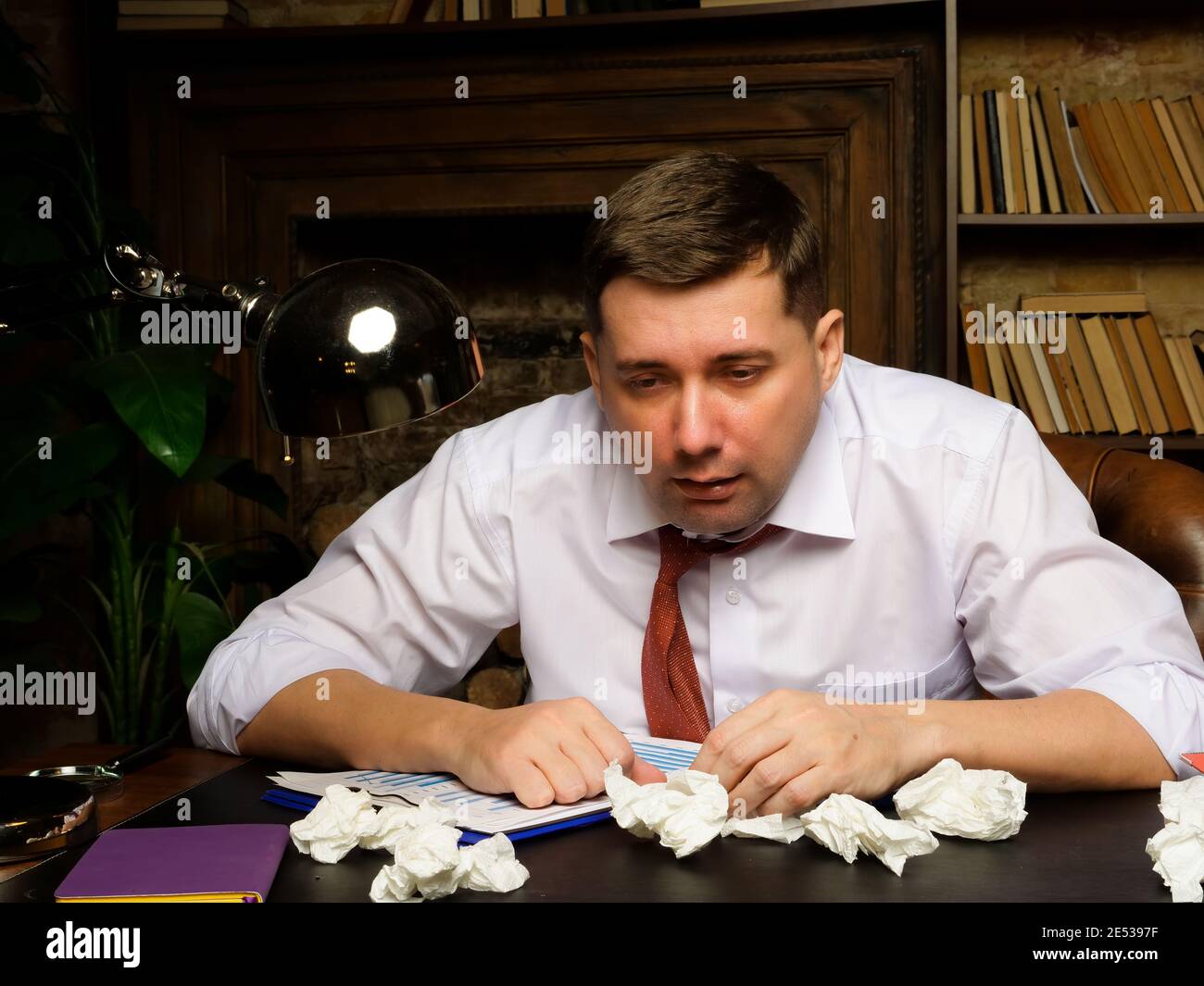 Sick male employee with a runny nose, or cold in the workplace. Stock Photo