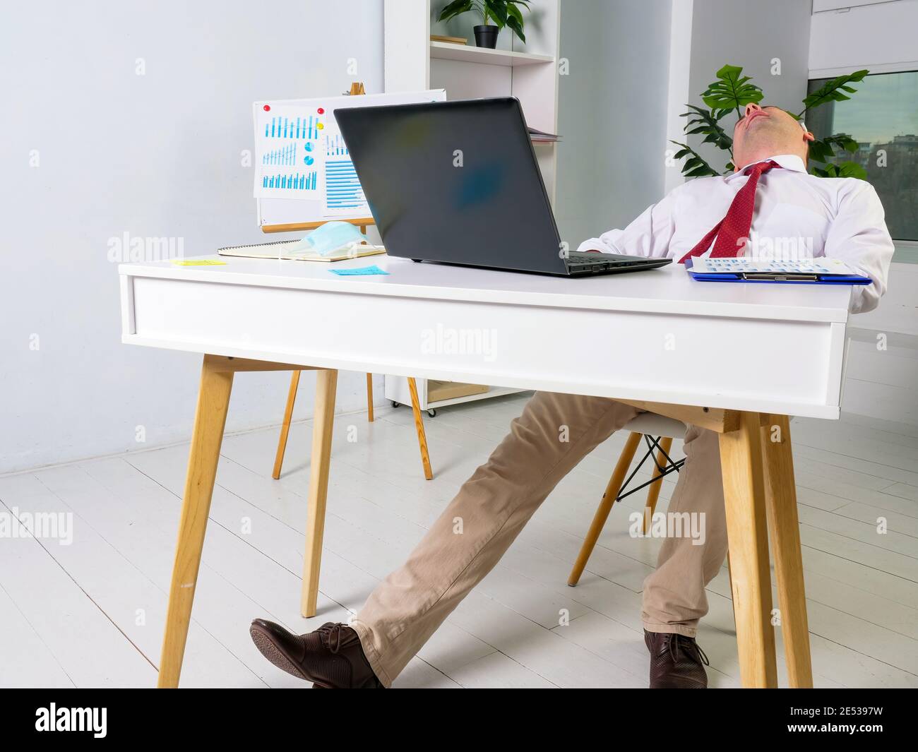 Tired male manager sleeps at the workplace. Overworking concept. Stock Photo