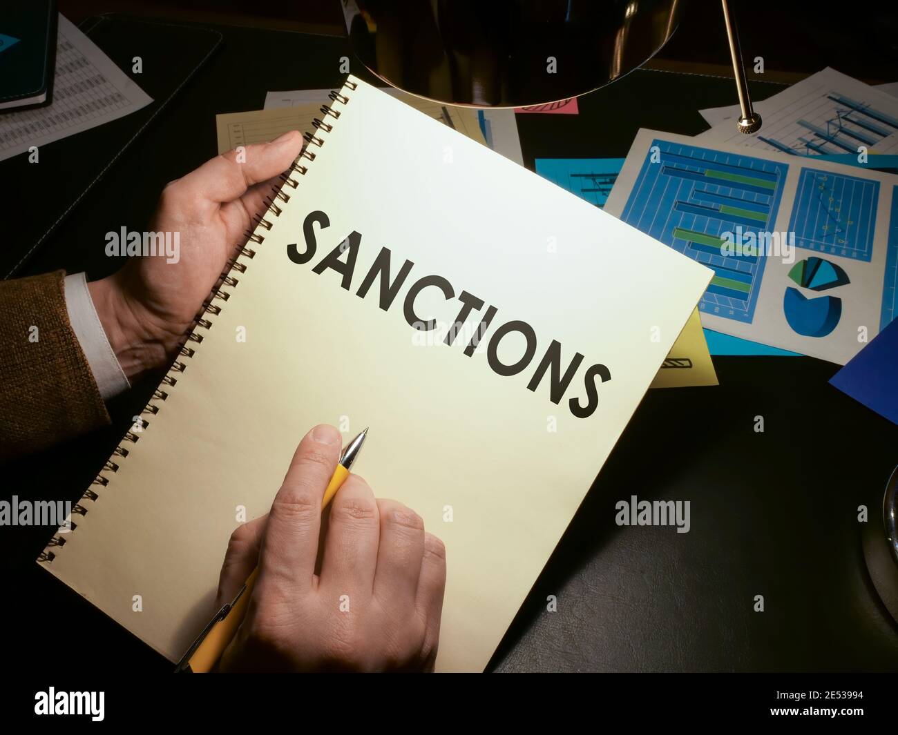 Hands hold a list of economic sanctions. Stock Photo