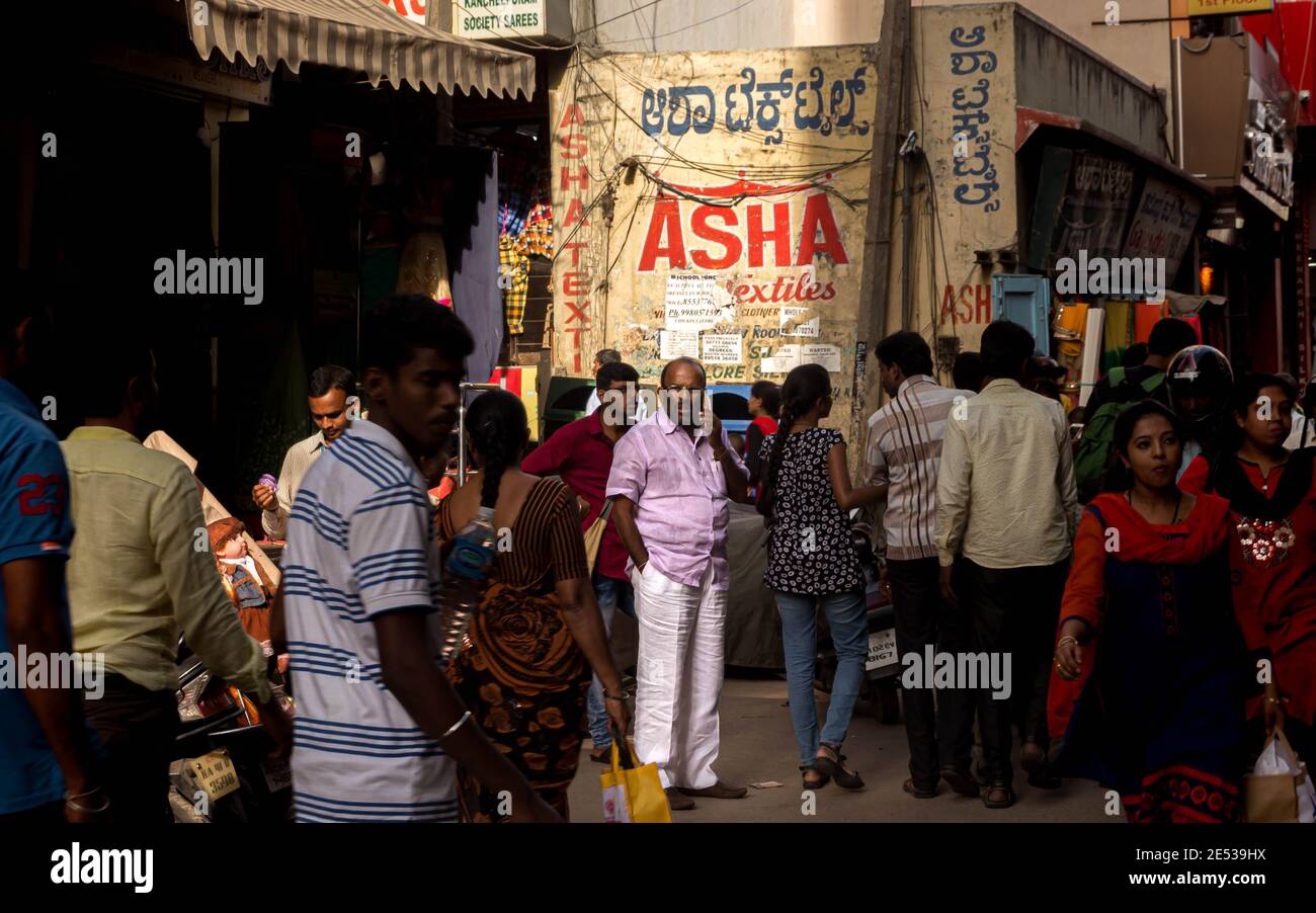 Busy and crowded Indian market street with an India man with a phone standing in light in Bangalore, India. Stock Photo