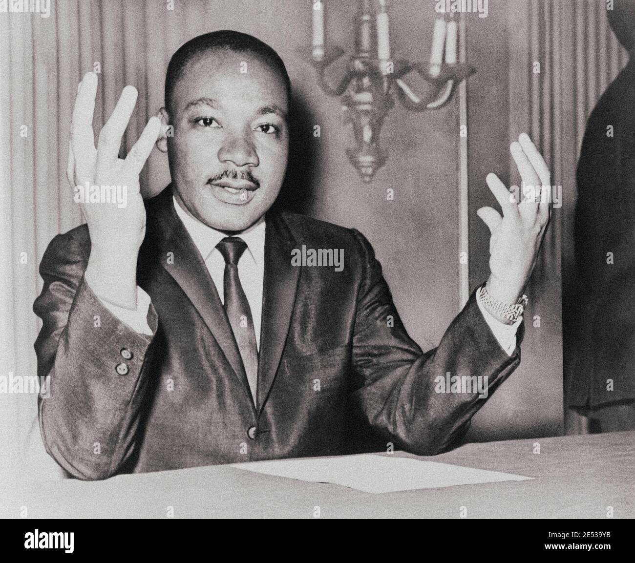 Rev. Martin Luther King, head-and-shoulders portrait, seated, facing front, hands extended upward, during a press conference. USA. November 6, 1964 Stock Photo