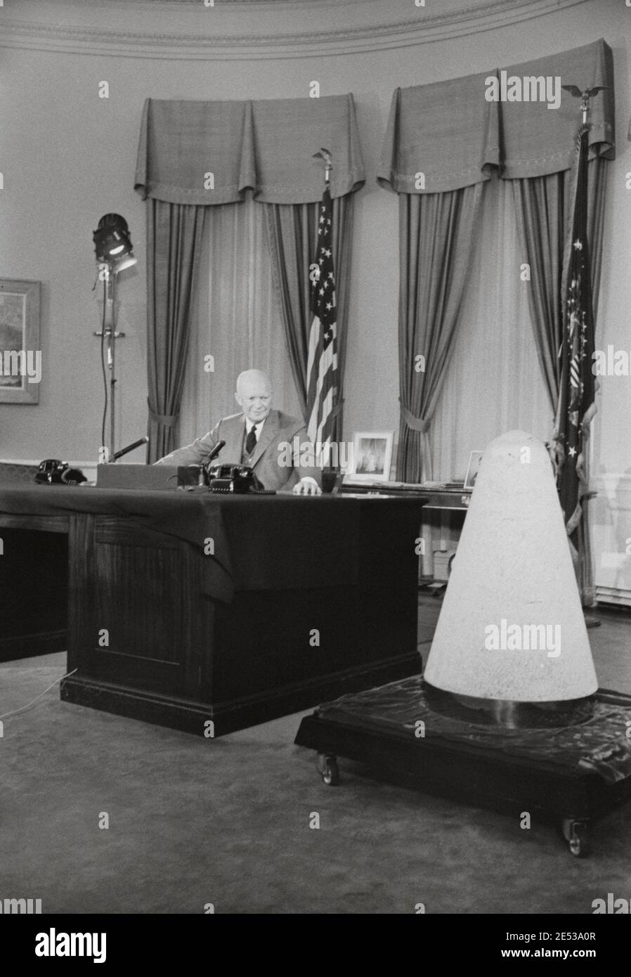 President Dwight Eisenhower giving a television speech in the White House about science and national security, next to a nose cone of an experimental Stock Photo
