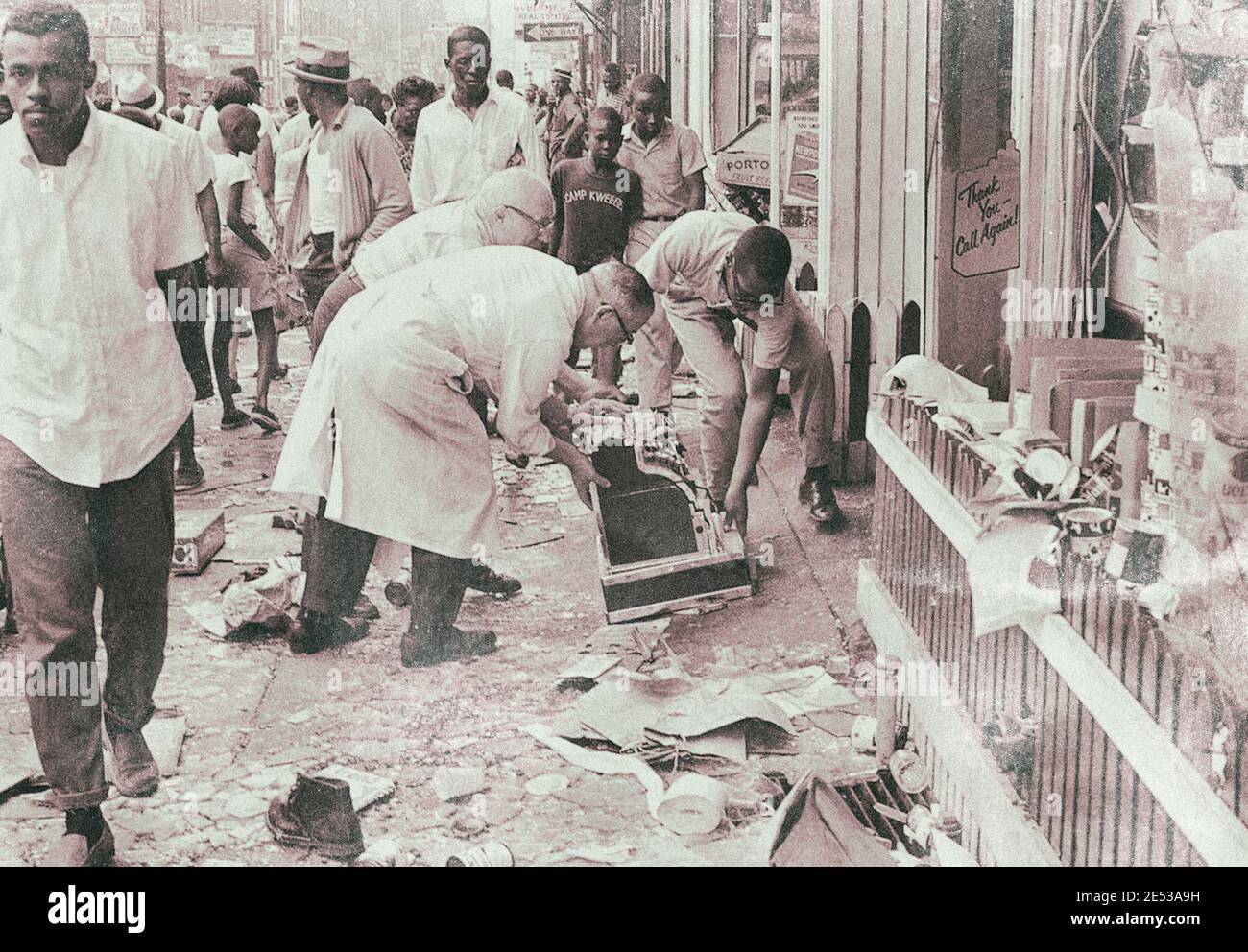 Workmen move a cash register off the sidewalk in front of smashed store, wrecked during wild night of looting and rioting in North Philadelphia, on Au Stock Photo