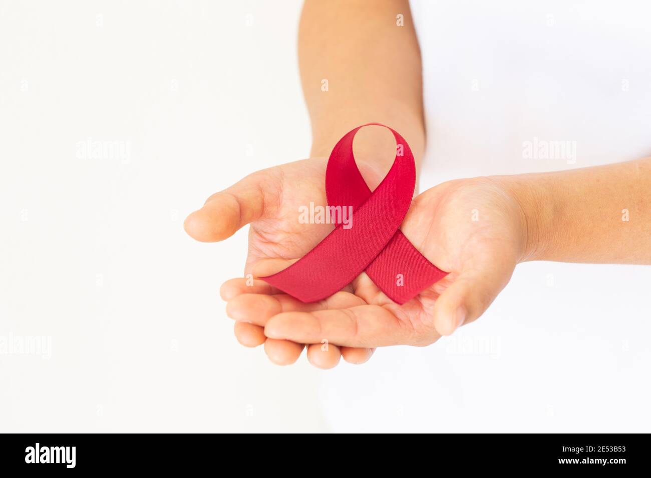 Hands holding red ribbon on white fabric with copy space, symbol for ...