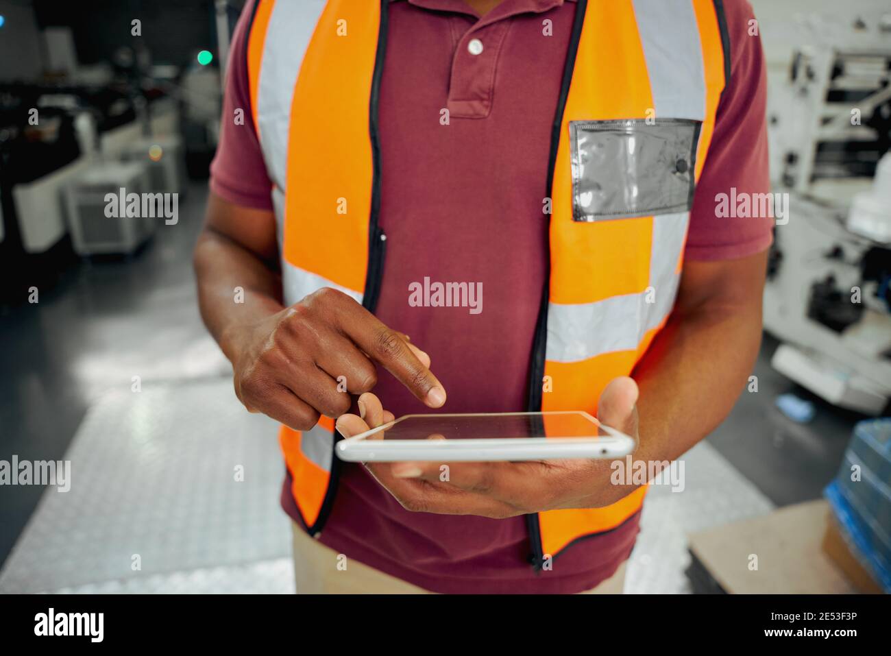 Midsection of a african american male factory worker typing on digital tablet in factory Stock Photo