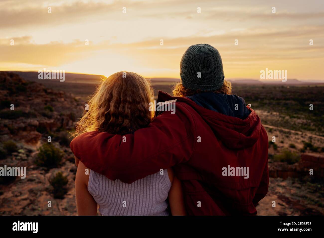 Romantic couple in love standing and embracing and watching mountain landscape in sunrise morning Stock Photo