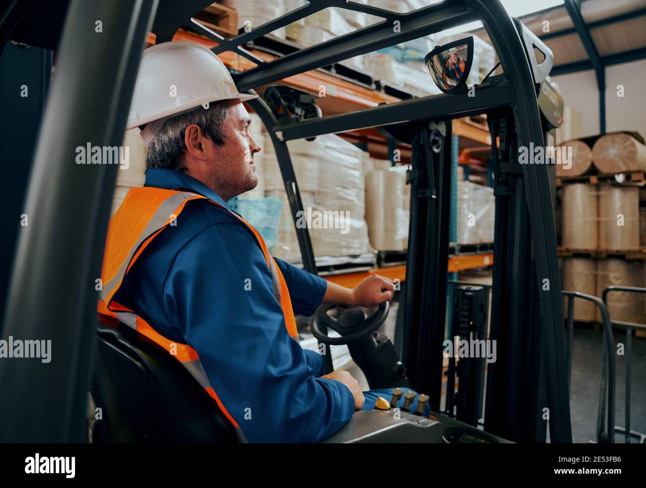 Side shot of a male worker driving the forklift truck in the warehouse Stock Photo