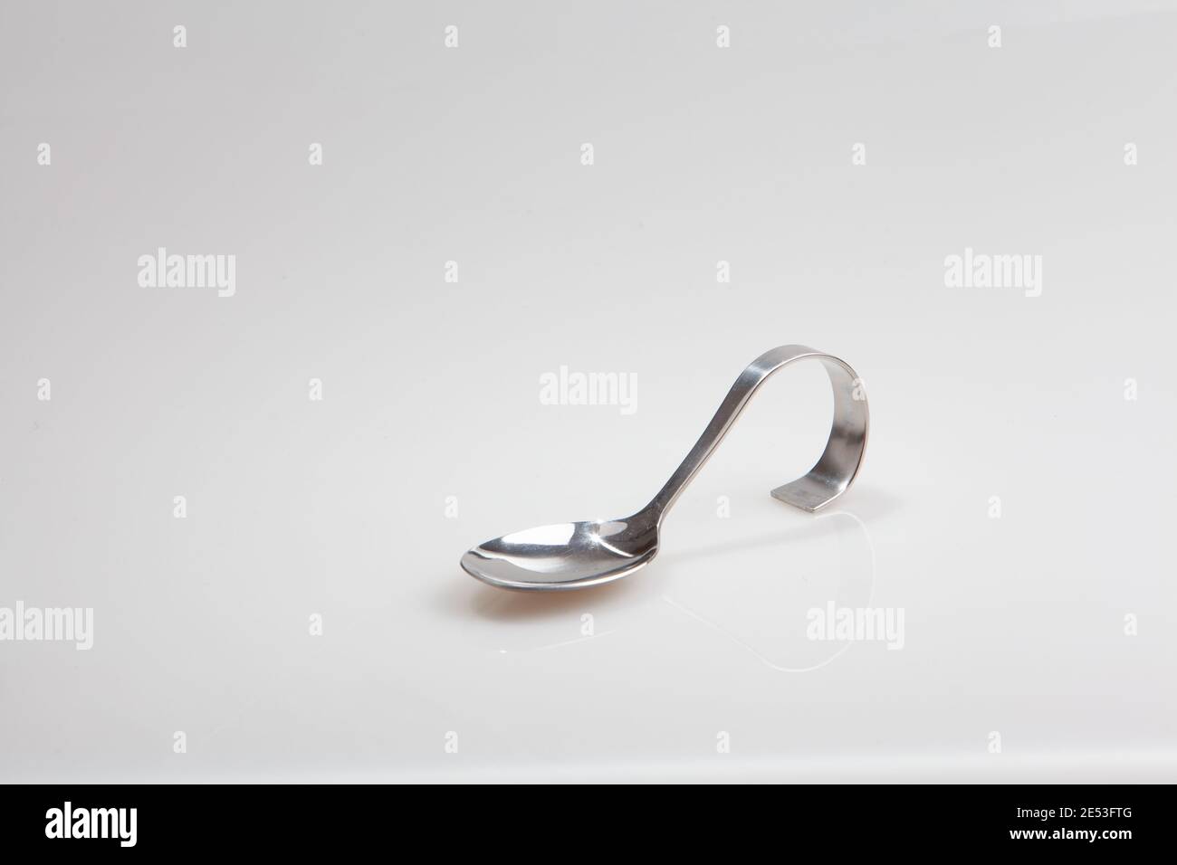A silver spoon with curved handle photographed half sideways isolated