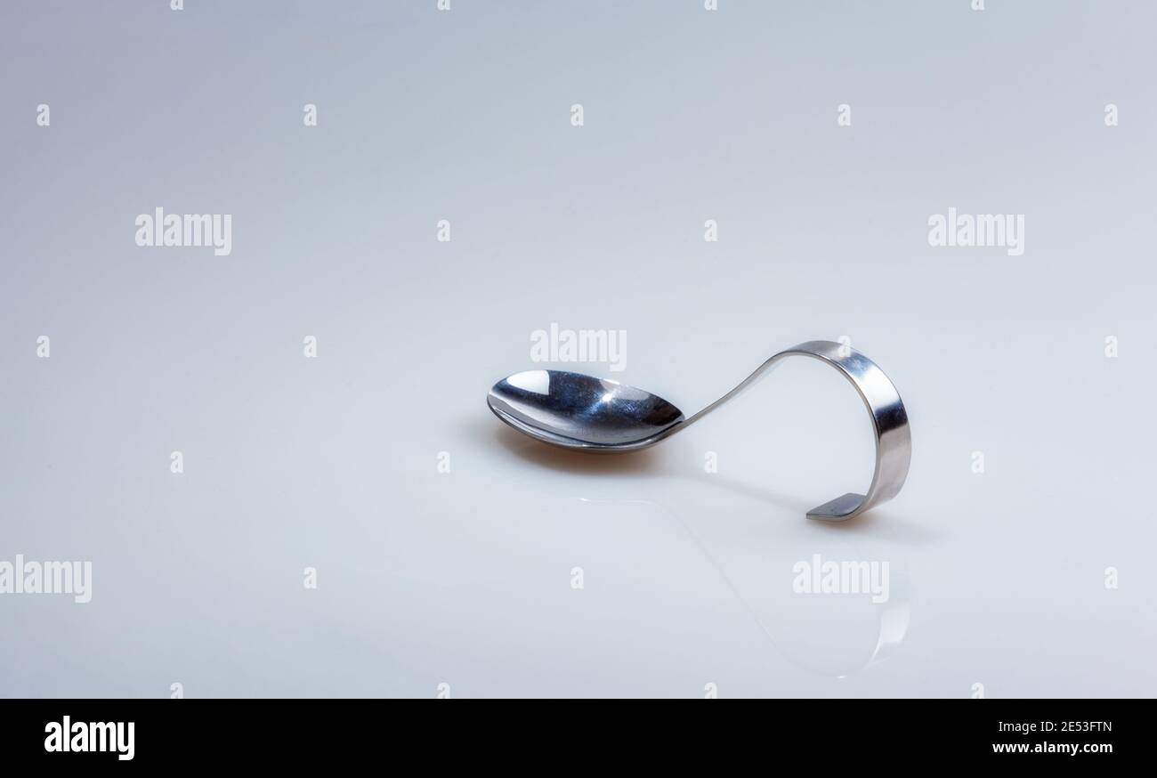 A silver spoon with curved handle photographed half sideways isolated