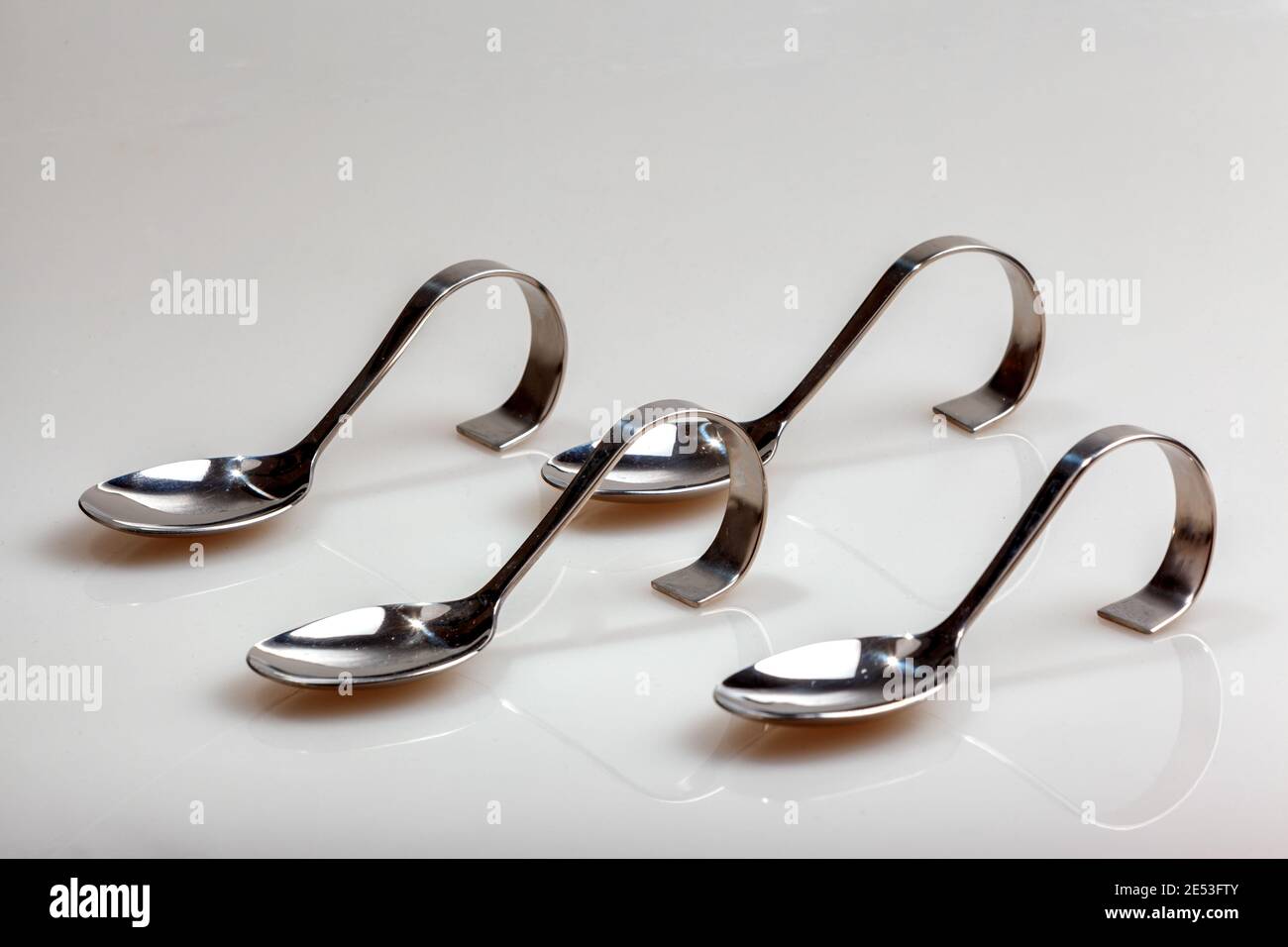 four silver spoons with curved handle photographed half sideways, placed inside each other and isolated on white Stock Photo