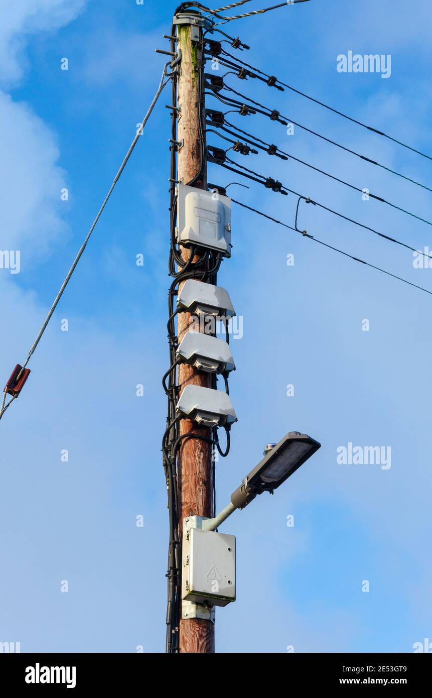 A wooden pole carries mains electricity cables and street lighting
