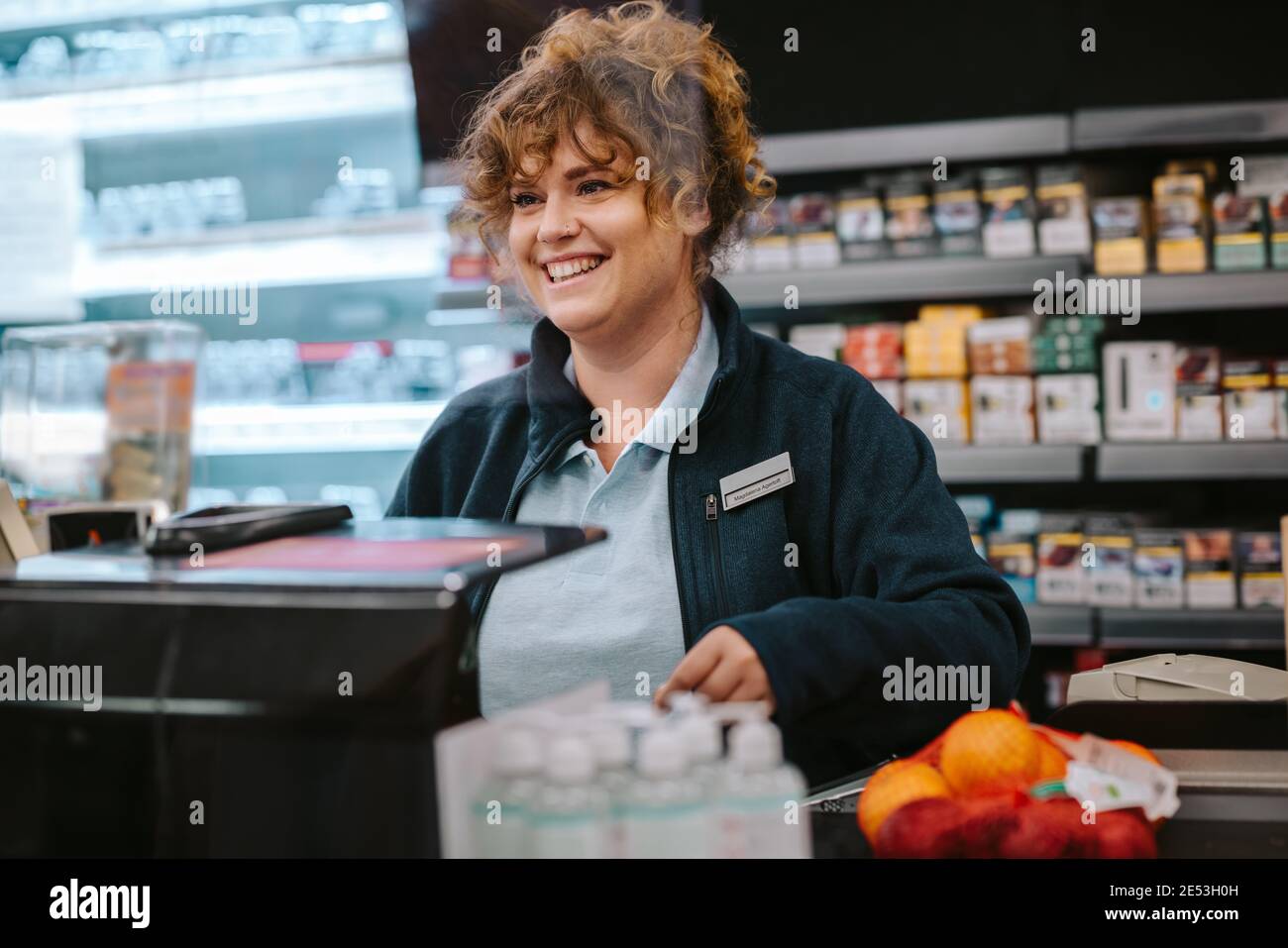Woman working as a cashier in a supermarket. She is smiling at the customer. Stock Photo