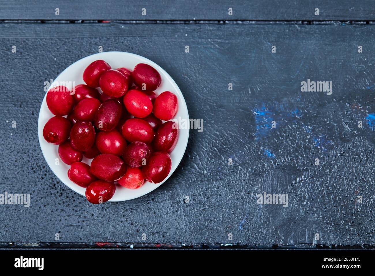 Bunch of cornel berries on white plate. Top view Stock Photo