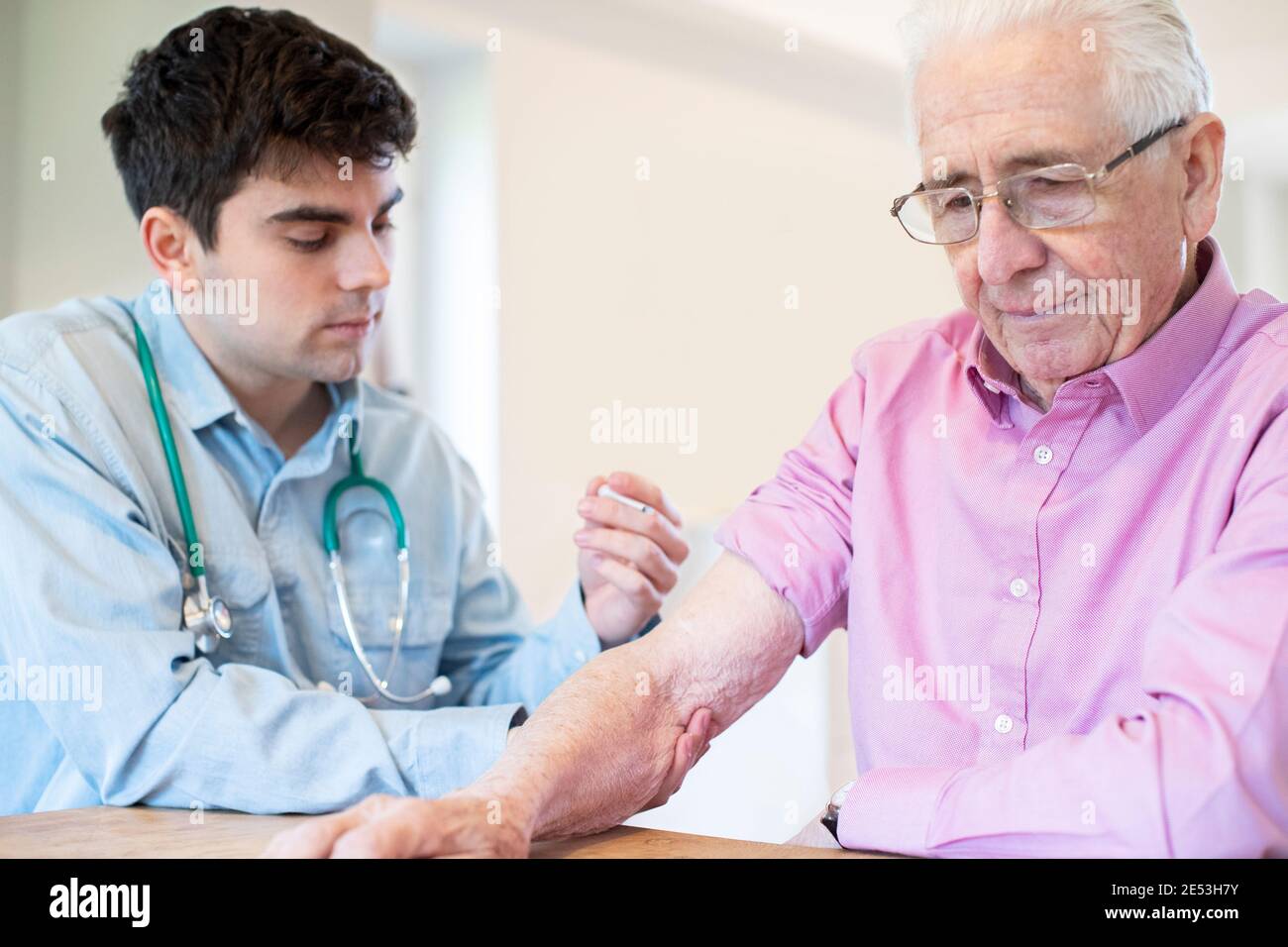Male Doctor Giving Senior Man Vaccine Injection In Arm With Syringe Stock Photo