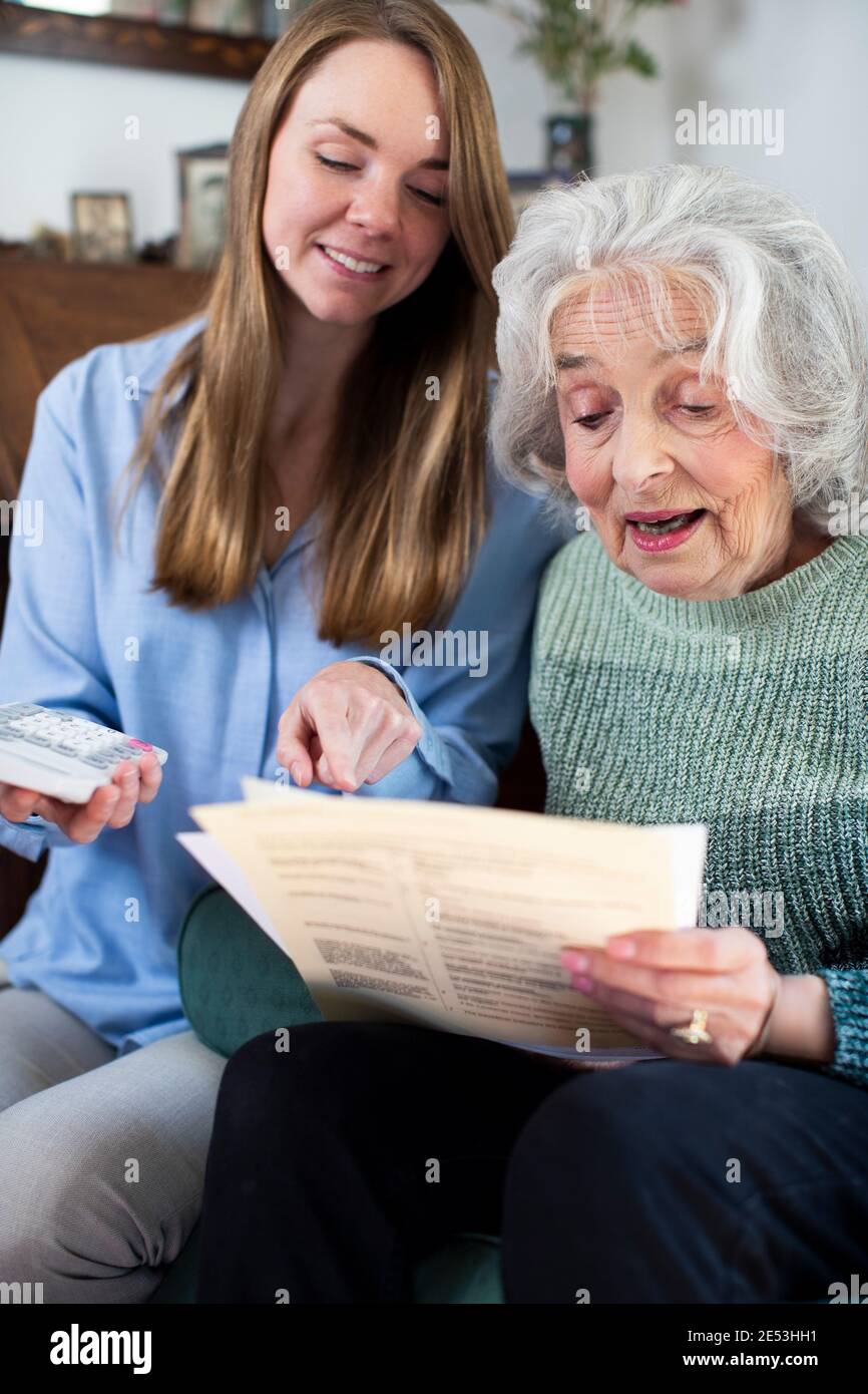 Woman Helping Senior Neighbor With Bills And Paperwork Stock Photo
