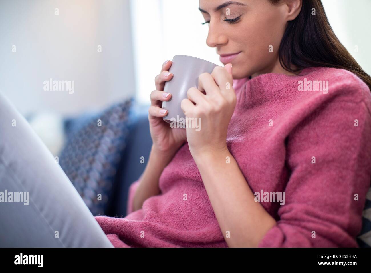 Young Woman Relaxing On Sofa At Home With Hot Drink Stock Photo - Alamy