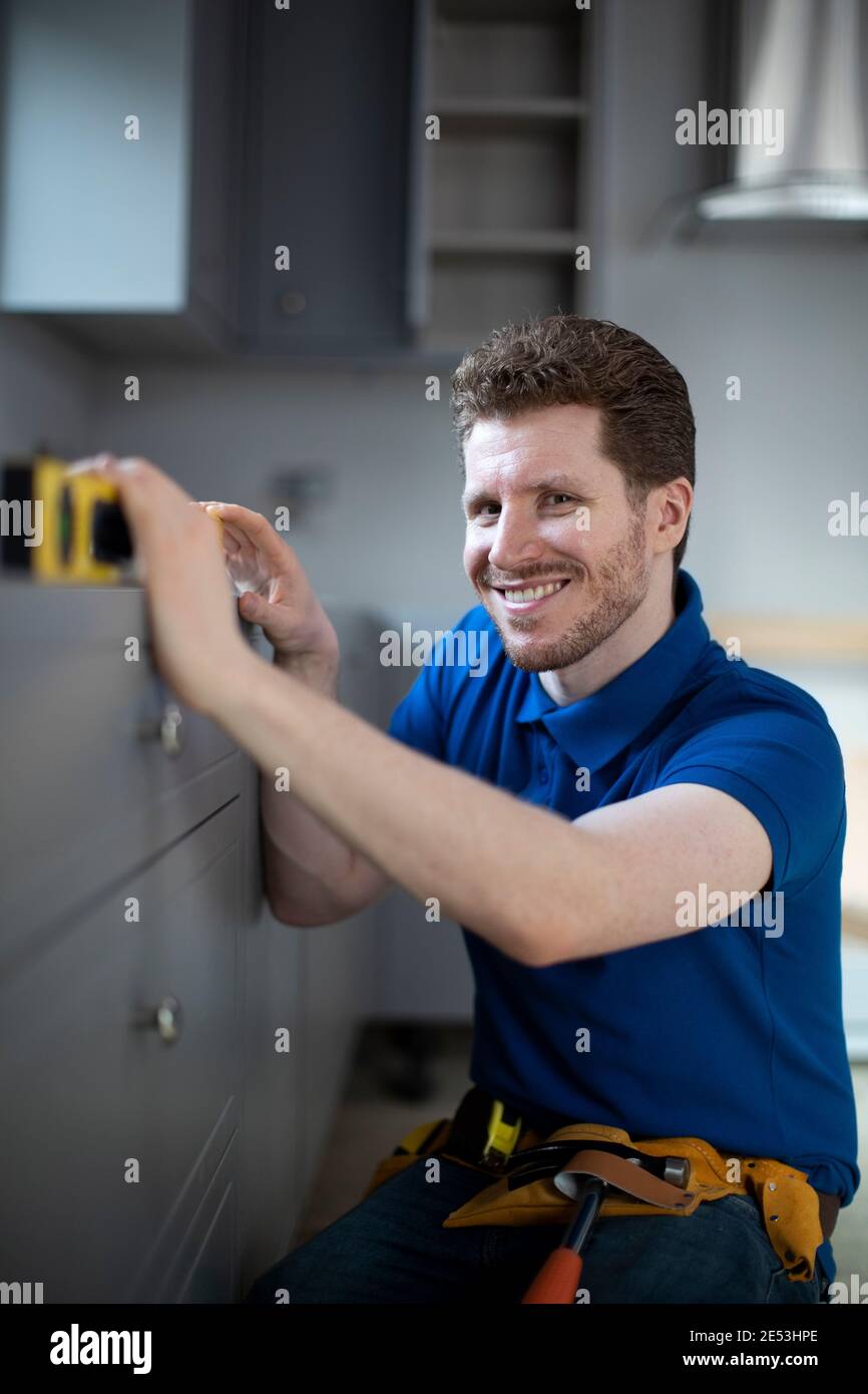 Portrait Of Carpenter Installing Luxury Modern Fitted Kitchen Stock
