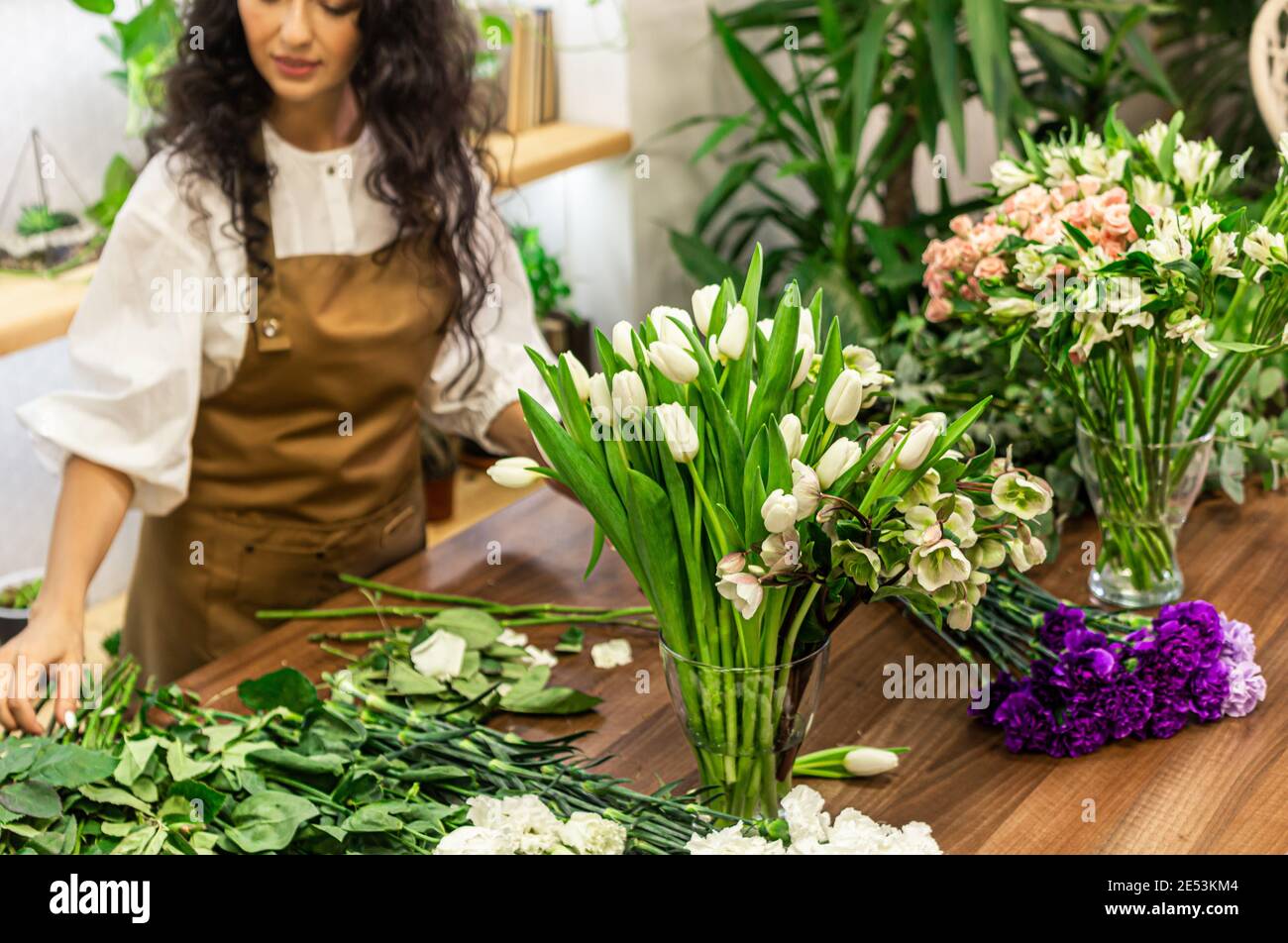 Attractive young woman florist is working in a flower shop Stock Photo ...