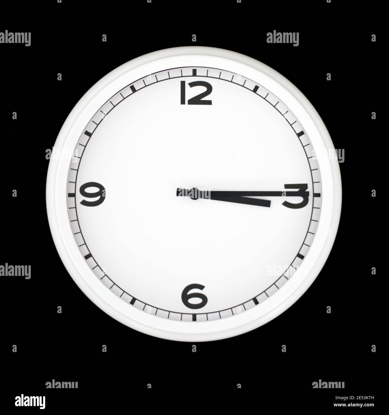 White round analog wall clock isolated on black background, its quarter