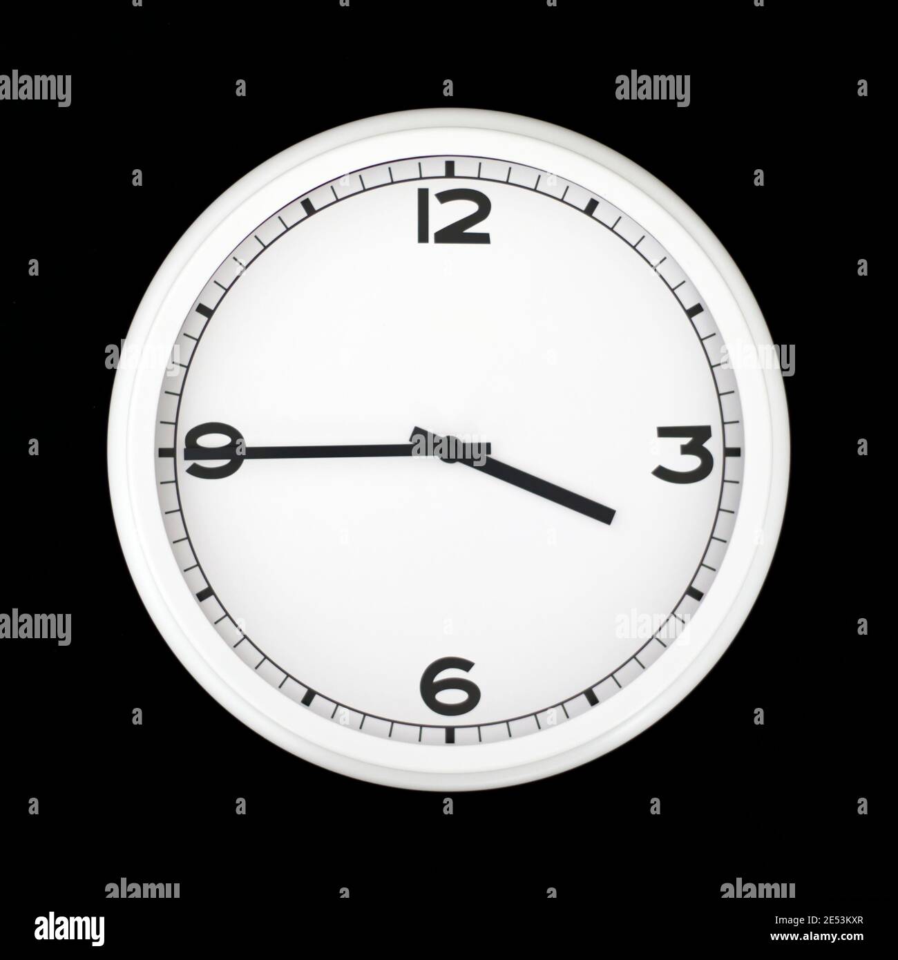 White round analog wall clock isolated on black background, its quarter