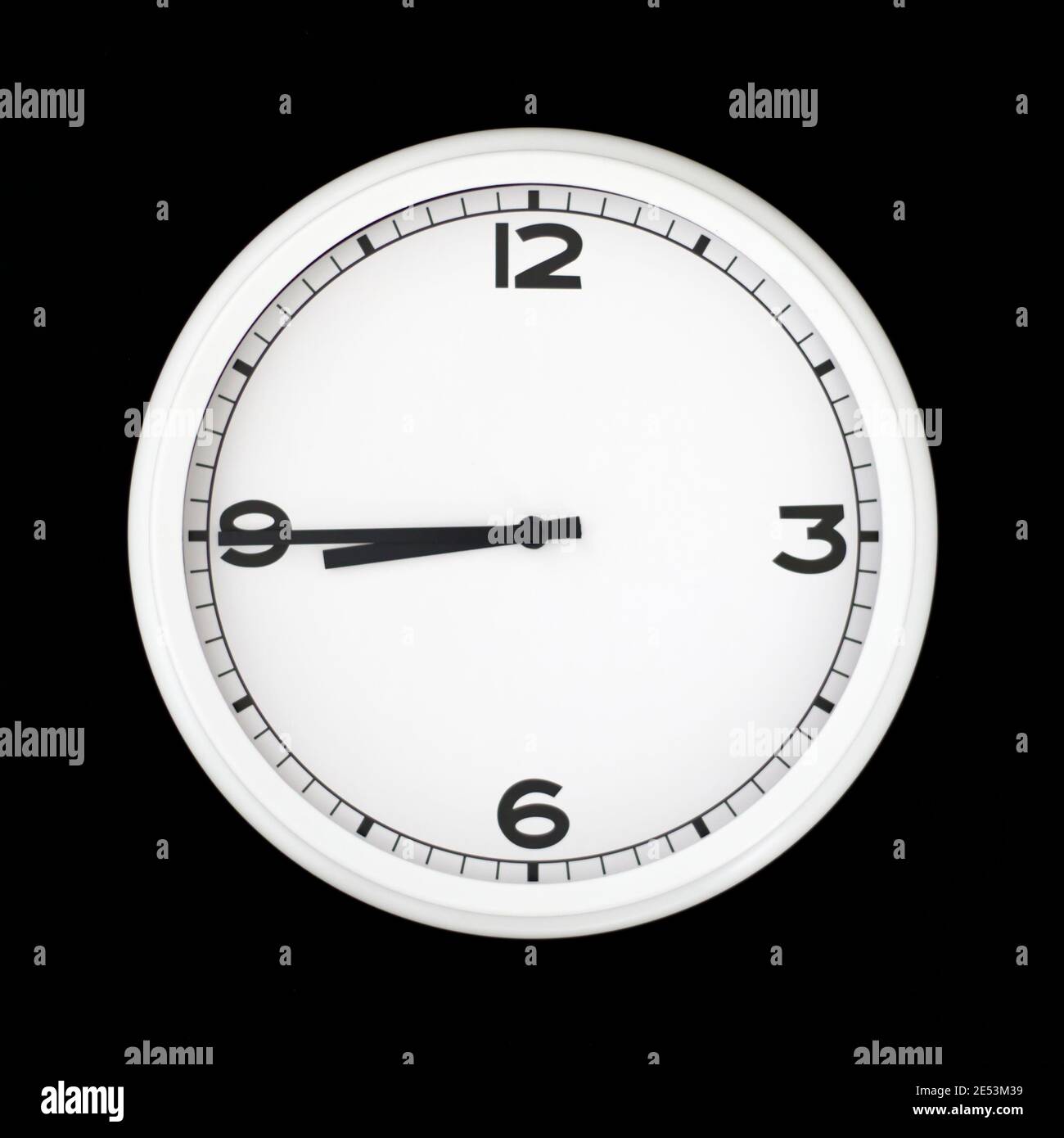 White round analog wall clock isolated on black background, its quarter