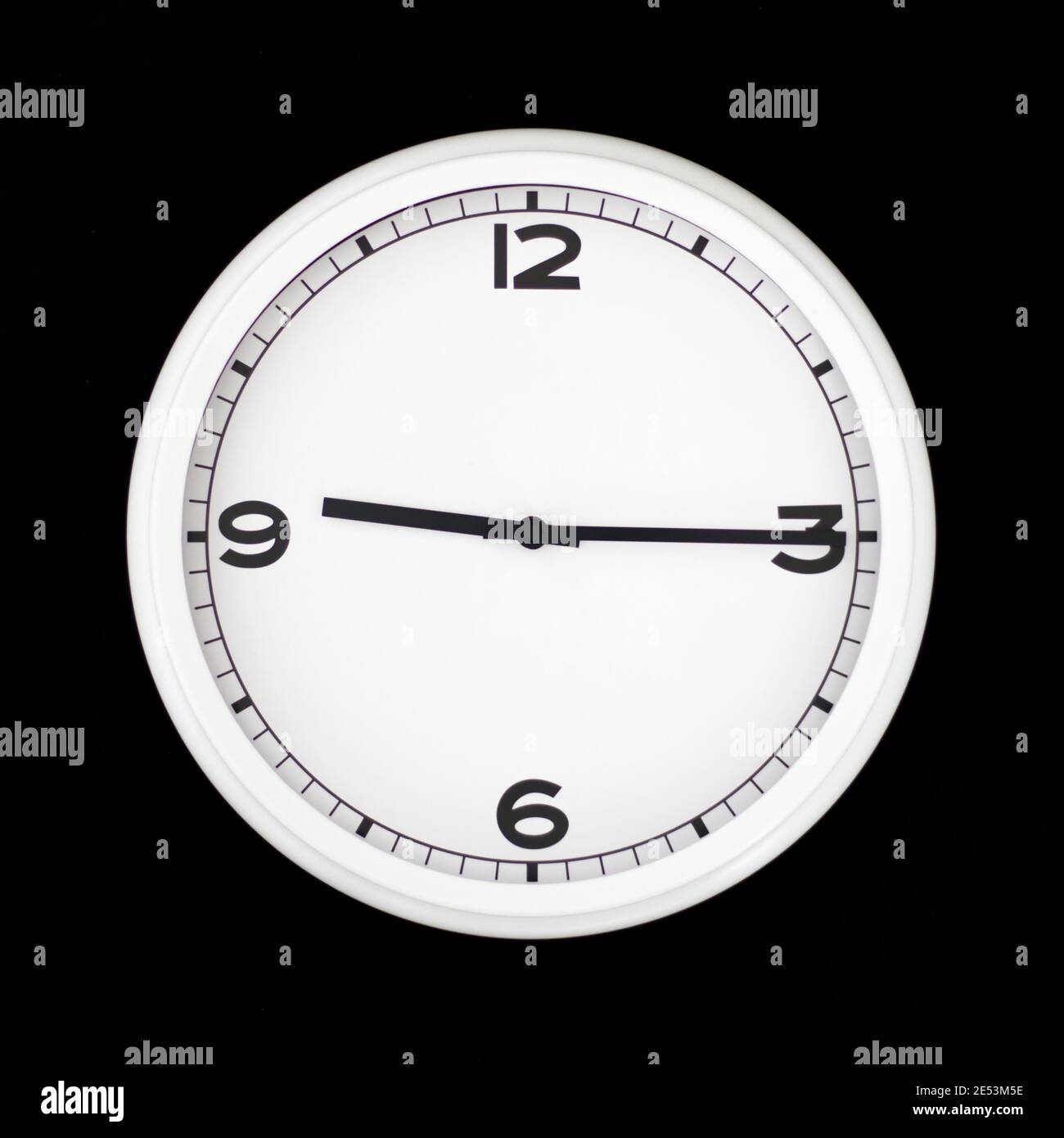 White round analog wall clock isolated on black background, its quarter