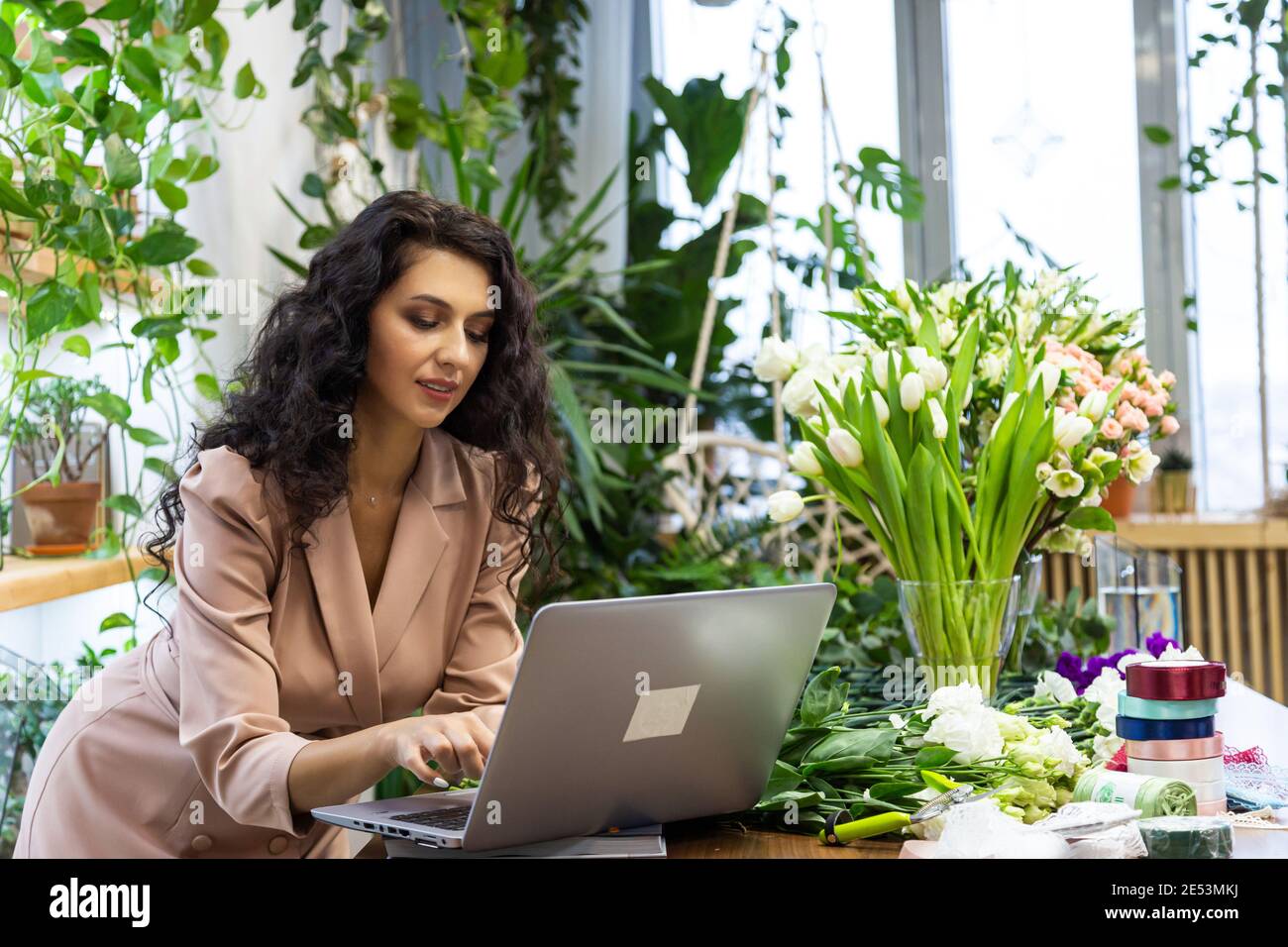 Attractive young woman florist is working in a flower shop Stock Photo ...