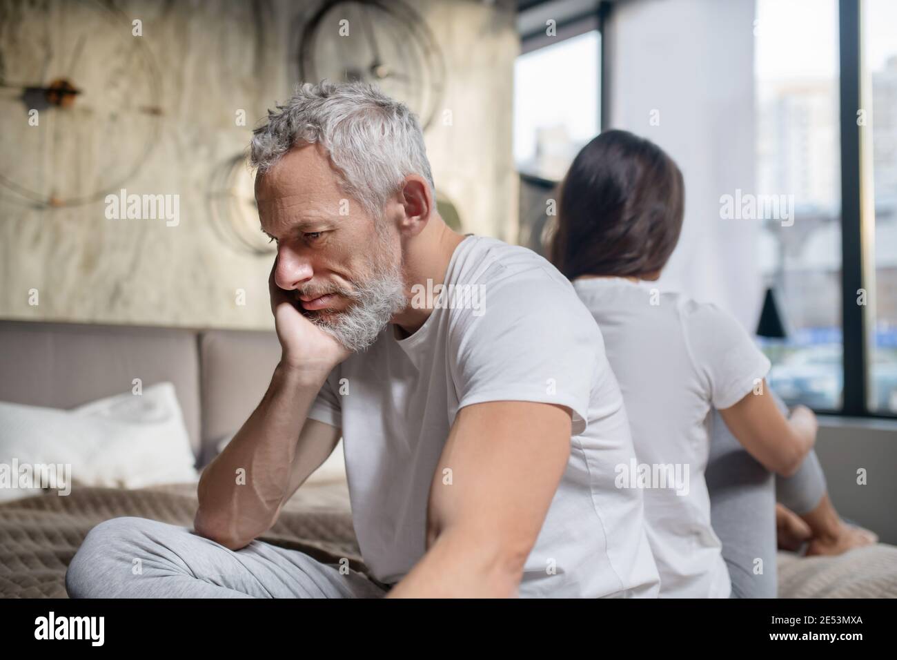 Unhappy man sitting back to back of woman Stock Photo