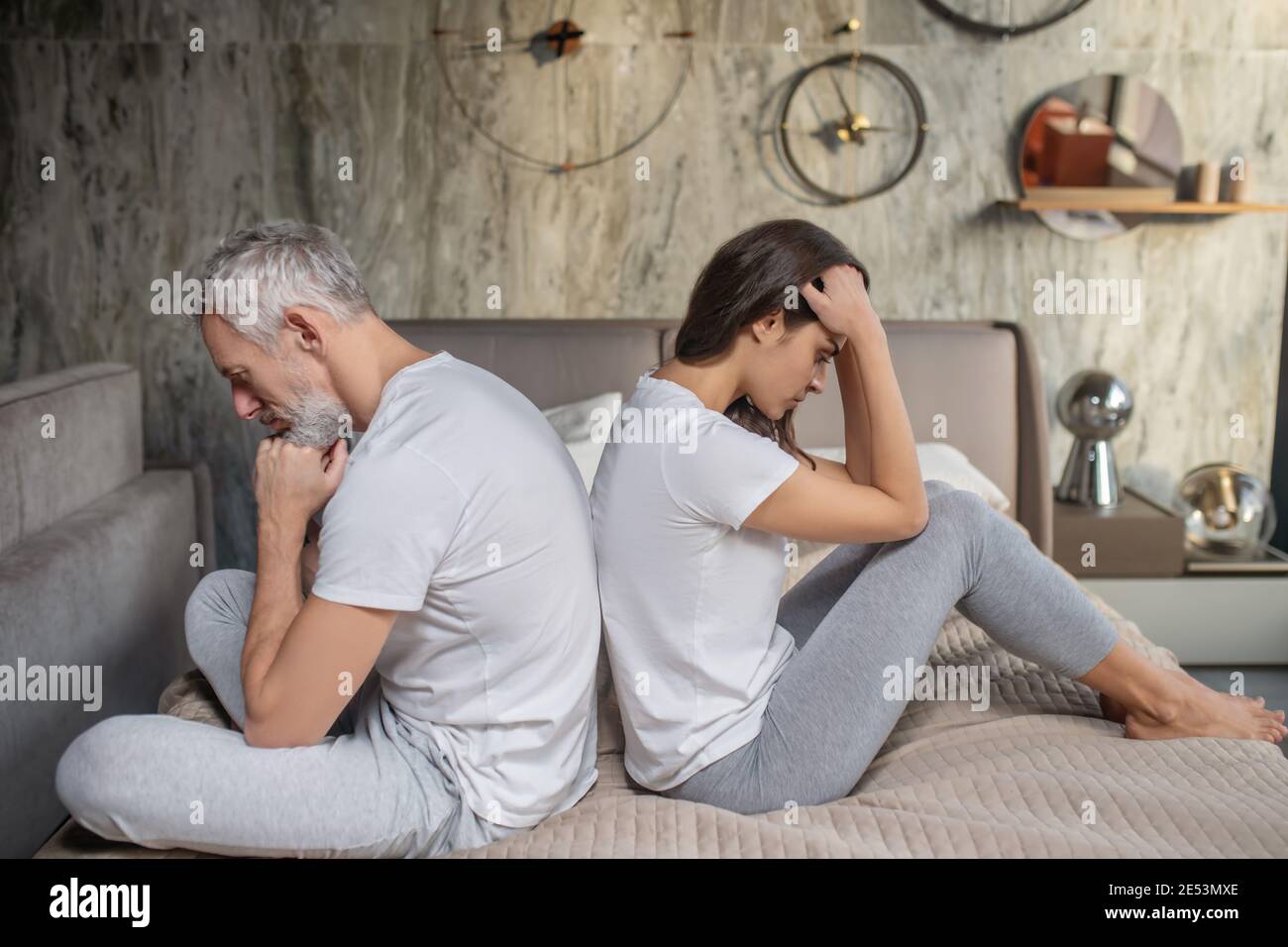 Turned away man and woman sitting on bed Stock Photo