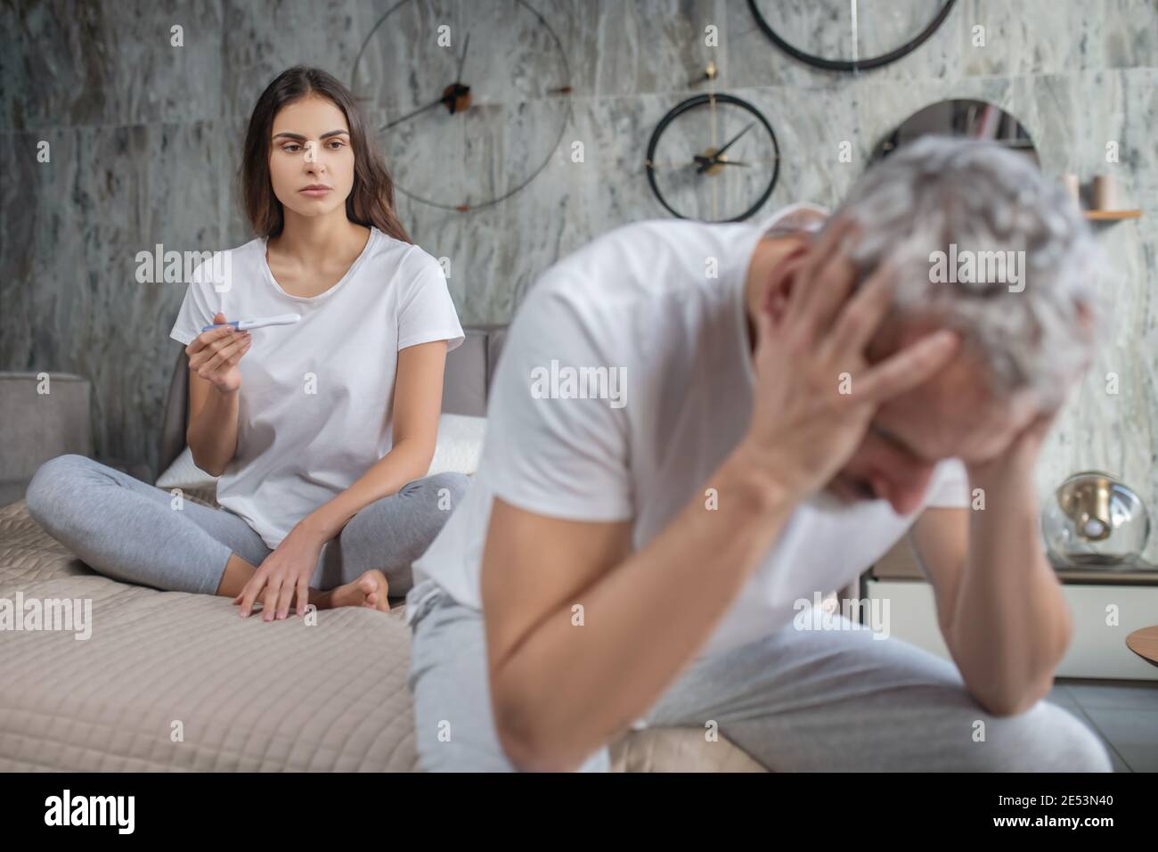 Sad woman with pregnancy test and puzzled man Stock Photo