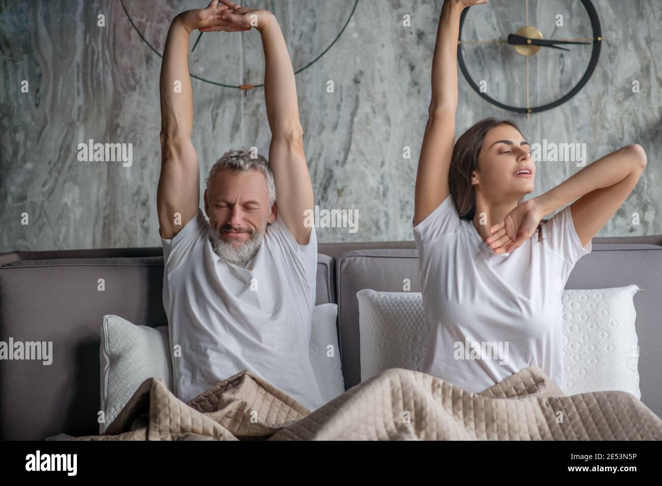 Man and woman waking up stretching in bed Stock Photo