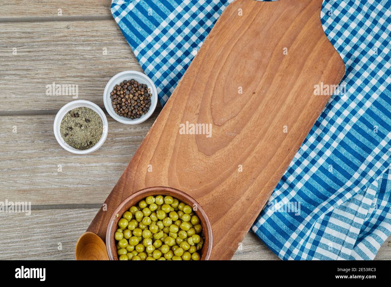 https://c8.alamy.com/comp/2E53RC3/a-bowl-of-boiled-green-peas-with-a-spoon-spices-and-a-blue-tablecloth-on-a-wooden-table-2E53RC3.jpg
