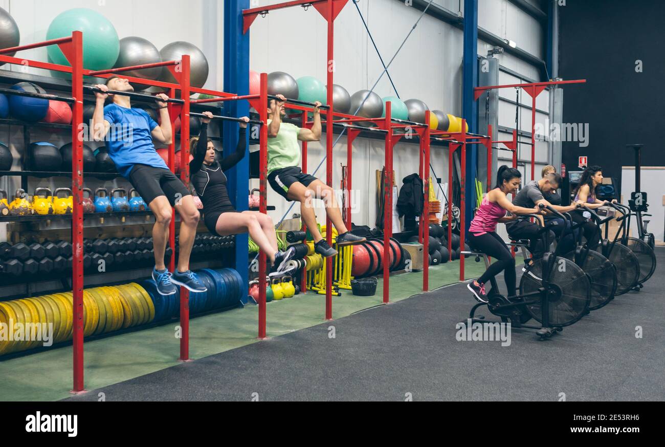 Athletes doing pull ups and air bike in the gym Stock Photo
