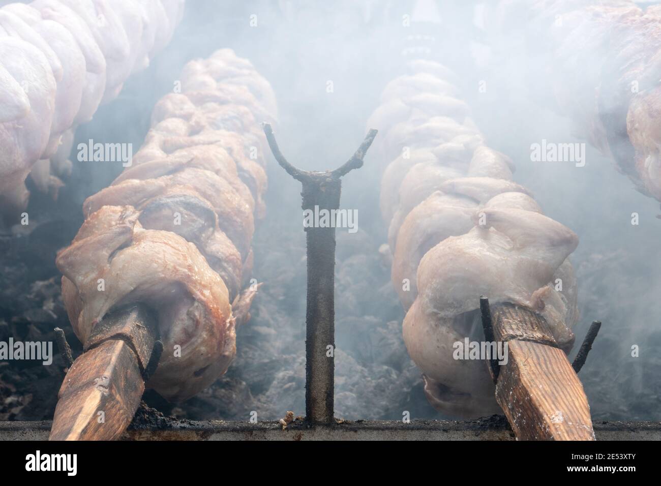 Chickens cooking on a barbecue grill with slowly rotating spits, skewers. Stock Photo