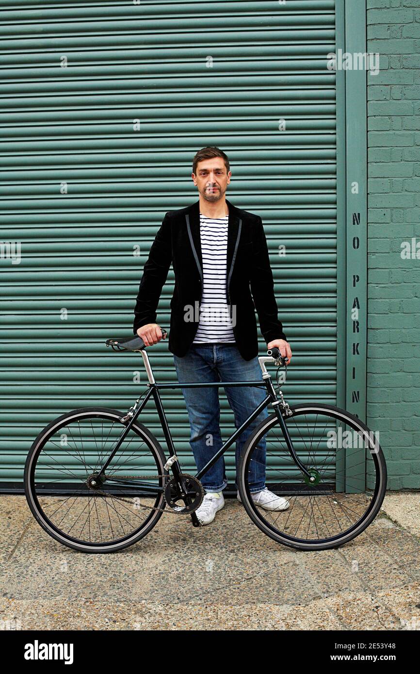 Man standing in front of black fixie bicycle Stock Photo