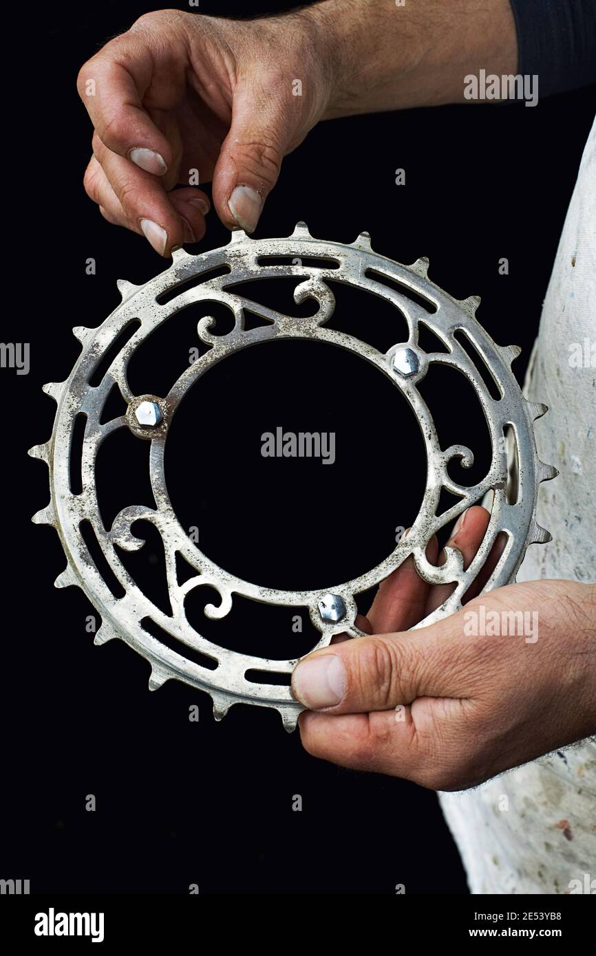 Bicycle mechanic holding old chain ring of a bicycle Stock Photo
