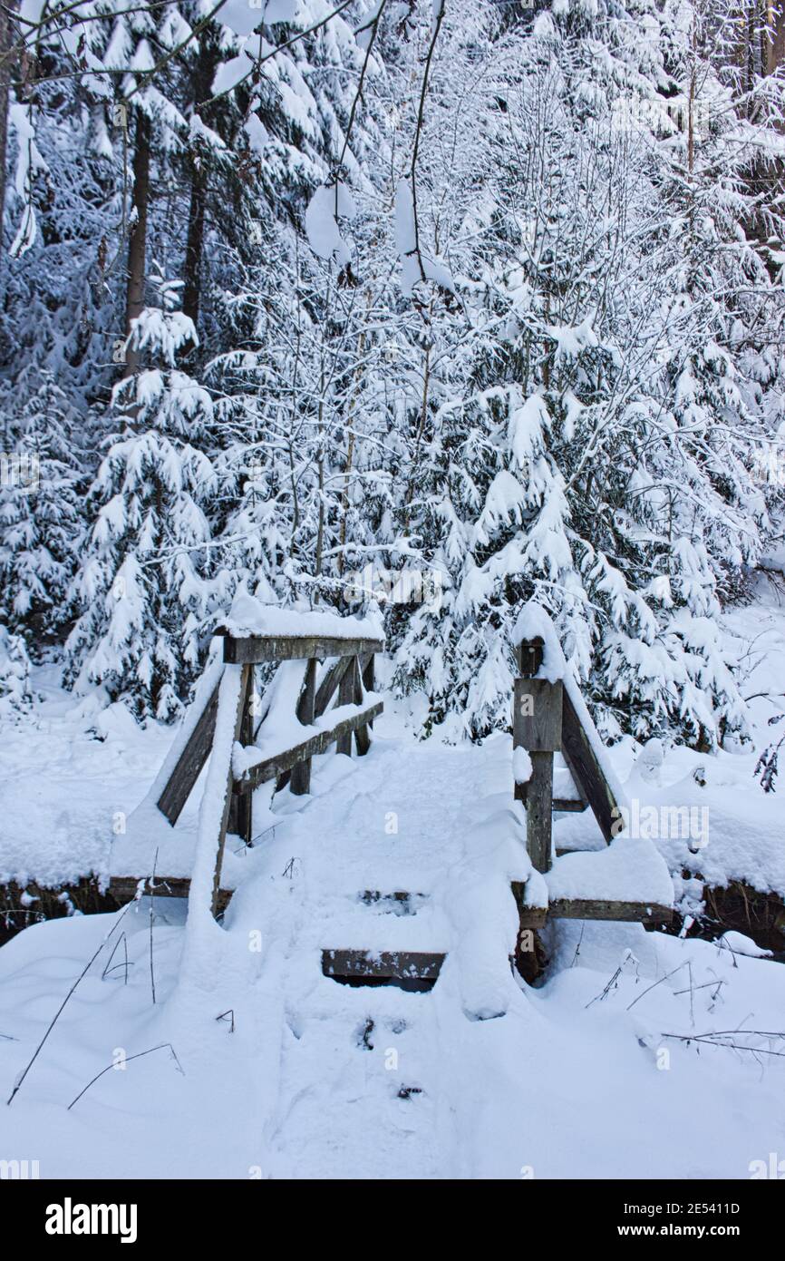 wooden bridge over small river in winter wonderland Stock Photo