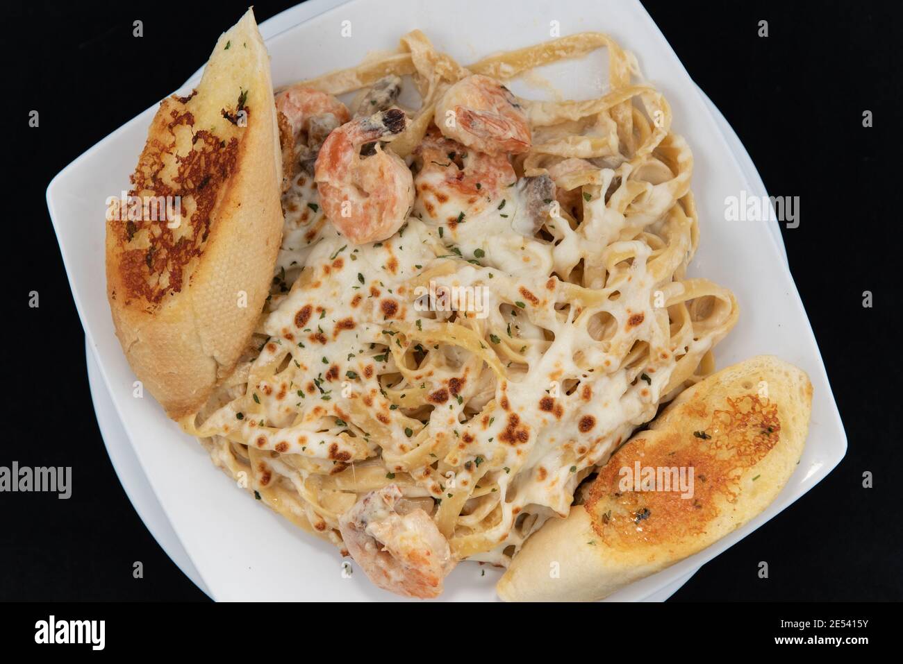 Overhead view of Mexican culinary favorite seafood pasta garnished with garlic bread on a plate. Stock Photo