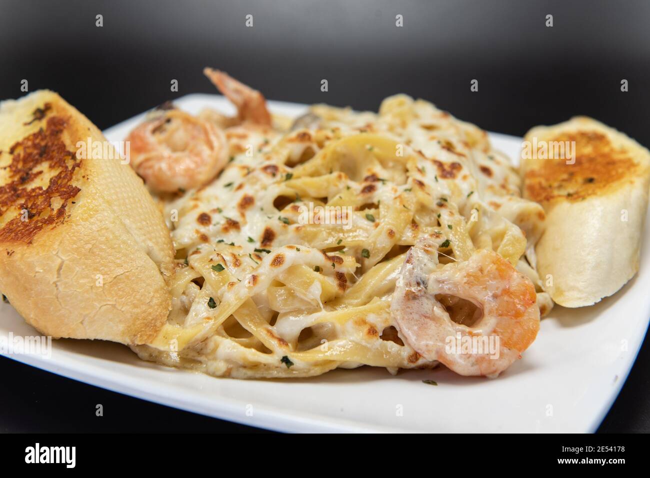 Mexican culinary favorite seafood pasta garnished with garlic bread on a plate. Stock Photo