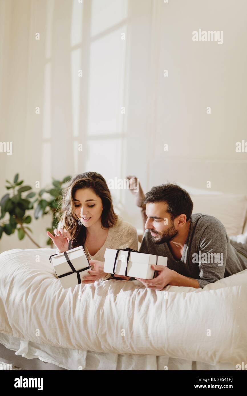Beautiful couple in love lying in the bed and make a present to each other on Valentine's Day. Stock Photo