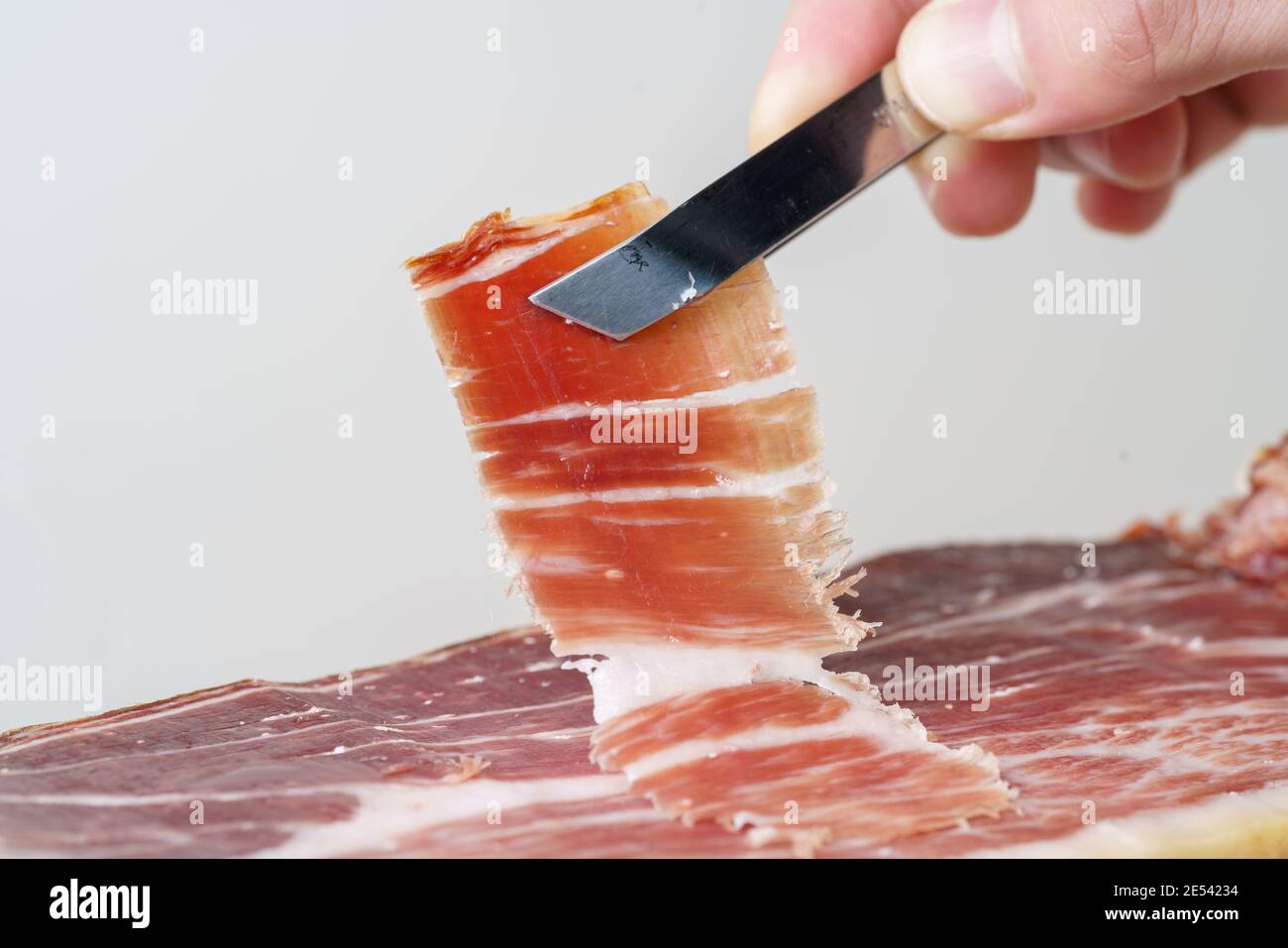 Freshly cut slice of acorn-fed Iberian ham, typical Spanish gourmet delicacy Stock Photo